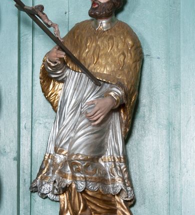 Zdjęcie nr 19: Nastawa ołtarzowa architektoniczna, jednokondygnacyjna, trójosiowa ze zwieńczeniem i z bramkami. Ołtarz prostopadłościenny, drewniany, mensa drewniana z kamiennym portatylem. Antependium w formie leżącego prostokąta ujętego złoconą, profilowaną ramą. W polu obraz malowany olejem na płótnie. W centrum kartusz w kształcie wydłużonego czwórliścia, dekorowany muszlą i wolutami z przedstawieniem pejzażu i widokiem na Golgotę. Po bokach kartusza bujne gałązki kwiatów. Tabernakulum w formie prostopadłościennej skrzynki o wypukłej ścianie frontowej, na profilowanym cokole, zamknięte profilowanym gzymsem, ujęte uszami utworzonymi z liści. Nad drzwiczkami, na gzymsie kartusz z niewielkim krucyfiksem. Powyżej tron wystawienia w formie profilowanej podstawy dekorowanej liśćmi. Na ściance frontowej tabernakulum profilowana rama w kształcie stojącego prostokąta zamkniętego łukiem nadwieszonym, w polu drzwiczki w formie stojącego prostokąta z przedstawieniem kielicha w glorii, powyżej drzwiczek winne grono. 

Nastawa ustawiona na zdwojonym cokole, dekorowanym wijącym się akantem. Osie kondygnacji wydzielone dwiema parami pilastrów oraz ustawionymi ukośnie kolumnami. Podpory dźwigają pełne belkowanie, przerwane nad polem środkowym i wyłamane nad osiami bocznymi, na których skraju ustawiony jest ukośnie przerwany, wolutowy przyczółek. Kolumny o kręconych trzonach, owinięte wicią liści akantu, kapitele korynckie; imposty ustawione pod kątem. W polu środkowym rama w kształcie stojącego prostokąta zamkniętego łukiem półkolistym z obrazem św. Kwiryna. W osiach bocznych płytkie płyciny, zwieńczone konchą z figurami św. Sebastiana po lewej stronie i św. Jana Nepomucena po prawej stronie, ustawionymi na wspornikach. Kondygnacja ujęta jest po bokach szerokimi uszami utworzonymi z liści akantu i karbowanej wstęgi. Fryz nad osiami bocznymi zdobiony kartuszami, we fryzie impostów z dwóch stron rozety; przyłucza osi bocznych dekorowane akantem.

W zwieńczeniu rzeźbiona półpostać Boga Ojca na obłoku z widocznym poniżej fragmentem globu ziemskiego i gołębicą Ducha Świętego; całość ukazana na tle promienistej glorii. Na belkowaniu, na osiach podpór wewnętrznych ustawione są rzeźby: św. Rocha  po lewej stronie i św. Wawrzyńca po prawej, a na zewnętrznych osiach retabulum rzeźby: Karola Boromeusza po lewej stronie i św. Stefana po prawej.

Nastawa ołtarzowa ujęta jest po bokach szerokimi bramkami w kształcie stojących prostokątów z drzwiczkami zamkniętymi półkoliście. Bramki ujęte są pilastrami o kanelowanych trzonach i fantazyjnych kapitelach, wspierających niepełne belkowanie oraz przerwany przyczółek. Nad bramkami ustawione są na cokołach rzeźby: św. Piotra po lewej stronie i św. Pawła po prawej. W polu drzwiczek owalne kartusze z herbem Görgey. W prawym kartuszu opisanym słowami: „BALTHAZAR GÖRGEI SENIOR”. Nad arkadami bramek są muszle, w przyłuczach akant, we fryzie rozety, a przerwany przyczółek dekorowany jest akantem. Struktura w całości polichromowana w odcieniu bladozielonym; ornamentyka, kolumny i profilowania złocone, detale srebrzone.