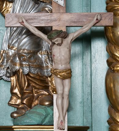 Zdjęcie nr 49: Nastawa ołtarzowa architektoniczna, jednokondygnacyjna, trójosiowa ze zwieńczeniem i z bramkami. Ołtarz prostopadłościenny, drewniany, mensa drewniana z kamiennym portatylem. Antependium w formie leżącego prostokąta ujętego złoconą, profilowaną ramą. W polu obraz malowany olejem na płótnie. W centrum kartusz w kształcie wydłużonego czwórliścia, dekorowany muszlą i wolutami z przedstawieniem pejzażu i widokiem na Golgotę. Po bokach kartusza bujne gałązki kwiatów. Tabernakulum w formie prostopadłościennej skrzynki o wypukłej ścianie frontowej, na profilowanym cokole, zamknięte profilowanym gzymsem, ujęte uszami utworzonymi z liści. Nad drzwiczkami, na gzymsie kartusz z niewielkim krucyfiksem. Powyżej tron wystawienia w formie profilowanej podstawy dekorowanej liśćmi. Na ściance frontowej tabernakulum profilowana rama w kształcie stojącego prostokąta zamkniętego łukiem nadwieszonym, w polu drzwiczki w formie stojącego prostokąta z przedstawieniem kielicha w glorii, powyżej drzwiczek winne grono. 

Nastawa ustawiona na zdwojonym cokole, dekorowanym wijącym się akantem. Osie kondygnacji wydzielone dwiema parami pilastrów oraz ustawionymi ukośnie kolumnami. Podpory dźwigają pełne belkowanie, przerwane nad polem środkowym i wyłamane nad osiami bocznymi, na których skraju ustawiony jest ukośnie przerwany, wolutowy przyczółek. Kolumny o kręconych trzonach, owinięte wicią liści akantu, kapitele korynckie; imposty ustawione pod kątem. W polu środkowym rama w kształcie stojącego prostokąta zamkniętego łukiem półkolistym z obrazem św. Kwiryna. W osiach bocznych płytkie płyciny, zwieńczone konchą z figurami św. Sebastiana po lewej stronie i św. Jana Nepomucena po prawej stronie, ustawionymi na wspornikach. Kondygnacja ujęta jest po bokach szerokimi uszami utworzonymi z liści akantu i karbowanej wstęgi. Fryz nad osiami bocznymi zdobiony kartuszami, we fryzie impostów z dwóch stron rozety; przyłucza osi bocznych dekorowane akantem.

W zwieńczeniu rzeźbiona półpostać Boga Ojca na obłoku z widocznym poniżej fragmentem globu ziemskiego i gołębicą Ducha Świętego; całość ukazana na tle promienistej glorii. Na belkowaniu, na osiach podpór wewnętrznych ustawione są rzeźby: św. Rocha  po lewej stronie i św. Wawrzyńca po prawej, a na zewnętrznych osiach retabulum rzeźby: Karola Boromeusza po lewej stronie i św. Stefana po prawej.

Nastawa ołtarzowa ujęta jest po bokach szerokimi bramkami w kształcie stojących prostokątów z drzwiczkami zamkniętymi półkoliście. Bramki ujęte są pilastrami o kanelowanych trzonach i fantazyjnych kapitelach, wspierających niepełne belkowanie oraz przerwany przyczółek. Nad bramkami ustawione są na cokołach rzeźby: św. Piotra po lewej stronie i św. Pawła po prawej. W polu drzwiczek owalne kartusze z herbem Görgey. W prawym kartuszu opisanym słowami: „BALTHAZAR GÖRGEI SENIOR”. Nad arkadami bramek są muszle, w przyłuczach akant, we fryzie rozety, a przerwany przyczółek dekorowany jest akantem. Struktura w całości polichromowana w odcieniu bladozielonym; ornamentyka, kolumny i profilowania złocone, detale srebrzone.