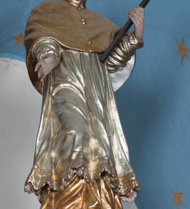 Zdjęcie nr 43: Nastawa ołtarzowa architektoniczna, jednokondygnacyjna, trójosiowa ze zwieńczeniem i z bramkami. Ołtarz prostopadłościenny, drewniany, mensa drewniana z kamiennym portatylem. Antependium w formie leżącego prostokąta ujętego złoconą, profilowaną ramą. W polu obraz malowany olejem na płótnie. W centrum kartusz w kształcie wydłużonego czwórliścia, dekorowany muszlą i wolutami z przedstawieniem pejzażu i widokiem na Golgotę. Po bokach kartusza bujne gałązki kwiatów. Tabernakulum w formie prostopadłościennej skrzynki o wypukłej ścianie frontowej, na profilowanym cokole, zamknięte profilowanym gzymsem, ujęte uszami utworzonymi z liści. Nad drzwiczkami, na gzymsie kartusz z niewielkim krucyfiksem. Powyżej tron wystawienia w formie profilowanej podstawy dekorowanej liśćmi. Na ściance frontowej tabernakulum profilowana rama w kształcie stojącego prostokąta zamkniętego łukiem nadwieszonym, w polu drzwiczki w formie stojącego prostokąta z przedstawieniem kielicha w glorii, powyżej drzwiczek winne grono. 

Nastawa ustawiona na zdwojonym cokole, dekorowanym wijącym się akantem. Osie kondygnacji wydzielone dwiema parami pilastrów oraz ustawionymi ukośnie kolumnami. Podpory dźwigają pełne belkowanie, przerwane nad polem środkowym i wyłamane nad osiami bocznymi, na których skraju ustawiony jest ukośnie przerwany, wolutowy przyczółek. Kolumny o kręconych trzonach, owinięte wicią liści akantu, kapitele korynckie; imposty ustawione pod kątem. W polu środkowym rama w kształcie stojącego prostokąta zamkniętego łukiem półkolistym z obrazem św. Kwiryna. W osiach bocznych płytkie płyciny, zwieńczone konchą z figurami św. Sebastiana po lewej stronie i św. Jana Nepomucena po prawej stronie, ustawionymi na wspornikach. Kondygnacja ujęta jest po bokach szerokimi uszami utworzonymi z liści akantu i karbowanej wstęgi. Fryz nad osiami bocznymi zdobiony kartuszami, we fryzie impostów z dwóch stron rozety; przyłucza osi bocznych dekorowane akantem.

W zwieńczeniu rzeźbiona półpostać Boga Ojca na obłoku z widocznym poniżej fragmentem globu ziemskiego i gołębicą Ducha Świętego; całość ukazana na tle promienistej glorii. Na belkowaniu, na osiach podpór wewnętrznych ustawione są rzeźby: św. Rocha  po lewej stronie i św. Wawrzyńca po prawej, a na zewnętrznych osiach retabulum rzeźby: Karola Boromeusza po lewej stronie i św. Stefana po prawej.

Nastawa ołtarzowa ujęta jest po bokach szerokimi bramkami w kształcie stojących prostokątów z drzwiczkami zamkniętymi półkoliście. Bramki ujęte są pilastrami o kanelowanych trzonach i fantazyjnych kapitelach, wspierających niepełne belkowanie oraz przerwany przyczółek. Nad bramkami ustawione są na cokołach rzeźby: św. Piotra po lewej stronie i św. Pawła po prawej. W polu drzwiczek owalne kartusze z herbem Görgey. W prawym kartuszu opisanym słowami: „BALTHAZAR GÖRGEI SENIOR”. Nad arkadami bramek są muszle, w przyłuczach akant, we fryzie rozety, a przerwany przyczółek dekorowany jest akantem. Struktura w całości polichromowana w odcieniu bladozielonym; ornamentyka, kolumny i profilowania złocone, detale srebrzone.