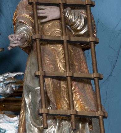 Zdjęcie nr 42: Nastawa ołtarzowa architektoniczna, jednokondygnacyjna, trójosiowa ze zwieńczeniem i z bramkami. Ołtarz prostopadłościenny, drewniany, mensa drewniana z kamiennym portatylem. Antependium w formie leżącego prostokąta ujętego złoconą, profilowaną ramą. W polu obraz malowany olejem na płótnie. W centrum kartusz w kształcie wydłużonego czwórliścia, dekorowany muszlą i wolutami z przedstawieniem pejzażu i widokiem na Golgotę. Po bokach kartusza bujne gałązki kwiatów. Tabernakulum w formie prostopadłościennej skrzynki o wypukłej ścianie frontowej, na profilowanym cokole, zamknięte profilowanym gzymsem, ujęte uszami utworzonymi z liści. Nad drzwiczkami, na gzymsie kartusz z niewielkim krucyfiksem. Powyżej tron wystawienia w formie profilowanej podstawy dekorowanej liśćmi. Na ściance frontowej tabernakulum profilowana rama w kształcie stojącego prostokąta zamkniętego łukiem nadwieszonym, w polu drzwiczki w formie stojącego prostokąta z przedstawieniem kielicha w glorii, powyżej drzwiczek winne grono. 

Nastawa ustawiona na zdwojonym cokole, dekorowanym wijącym się akantem. Osie kondygnacji wydzielone dwiema parami pilastrów oraz ustawionymi ukośnie kolumnami. Podpory dźwigają pełne belkowanie, przerwane nad polem środkowym i wyłamane nad osiami bocznymi, na których skraju ustawiony jest ukośnie przerwany, wolutowy przyczółek. Kolumny o kręconych trzonach, owinięte wicią liści akantu, kapitele korynckie; imposty ustawione pod kątem. W polu środkowym rama w kształcie stojącego prostokąta zamkniętego łukiem półkolistym z obrazem św. Kwiryna. W osiach bocznych płytkie płyciny, zwieńczone konchą z figurami św. Sebastiana po lewej stronie i św. Jana Nepomucena po prawej stronie, ustawionymi na wspornikach. Kondygnacja ujęta jest po bokach szerokimi uszami utworzonymi z liści akantu i karbowanej wstęgi. Fryz nad osiami bocznymi zdobiony kartuszami, we fryzie impostów z dwóch stron rozety; przyłucza osi bocznych dekorowane akantem.

W zwieńczeniu rzeźbiona półpostać Boga Ojca na obłoku z widocznym poniżej fragmentem globu ziemskiego i gołębicą Ducha Świętego; całość ukazana na tle promienistej glorii. Na belkowaniu, na osiach podpór wewnętrznych ustawione są rzeźby: św. Rocha  po lewej stronie i św. Wawrzyńca po prawej, a na zewnętrznych osiach retabulum rzeźby: Karola Boromeusza po lewej stronie i św. Stefana po prawej.

Nastawa ołtarzowa ujęta jest po bokach szerokimi bramkami w kształcie stojących prostokątów z drzwiczkami zamkniętymi półkoliście. Bramki ujęte są pilastrami o kanelowanych trzonach i fantazyjnych kapitelach, wspierających niepełne belkowanie oraz przerwany przyczółek. Nad bramkami ustawione są na cokołach rzeźby: św. Piotra po lewej stronie i św. Pawła po prawej. W polu drzwiczek owalne kartusze z herbem Görgey. W prawym kartuszu opisanym słowami: „BALTHAZAR GÖRGEI SENIOR”. Nad arkadami bramek są muszle, w przyłuczach akant, we fryzie rozety, a przerwany przyczółek dekorowany jest akantem. Struktura w całości polichromowana w odcieniu bladozielonym; ornamentyka, kolumny i profilowania złocone, detale srebrzone.