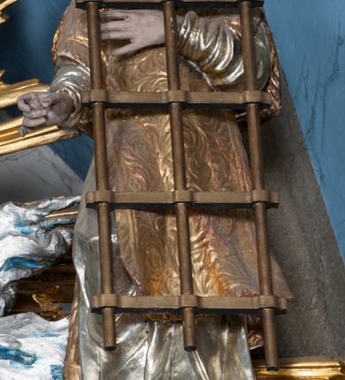 Zdjęcie nr 41: Nastawa ołtarzowa architektoniczna, jednokondygnacyjna, trójosiowa ze zwieńczeniem i z bramkami. Ołtarz prostopadłościenny, drewniany, mensa drewniana z kamiennym portatylem. Antependium w formie leżącego prostokąta ujętego złoconą, profilowaną ramą. W polu obraz malowany olejem na płótnie. W centrum kartusz w kształcie wydłużonego czwórliścia, dekorowany muszlą i wolutami z przedstawieniem pejzażu i widokiem na Golgotę. Po bokach kartusza bujne gałązki kwiatów. Tabernakulum w formie prostopadłościennej skrzynki o wypukłej ścianie frontowej, na profilowanym cokole, zamknięte profilowanym gzymsem, ujęte uszami utworzonymi z liści. Nad drzwiczkami, na gzymsie kartusz z niewielkim krucyfiksem. Powyżej tron wystawienia w formie profilowanej podstawy dekorowanej liśćmi. Na ściance frontowej tabernakulum profilowana rama w kształcie stojącego prostokąta zamkniętego łukiem nadwieszonym, w polu drzwiczki w formie stojącego prostokąta z przedstawieniem kielicha w glorii, powyżej drzwiczek winne grono. 

Nastawa ustawiona na zdwojonym cokole, dekorowanym wijącym się akantem. Osie kondygnacji wydzielone dwiema parami pilastrów oraz ustawionymi ukośnie kolumnami. Podpory dźwigają pełne belkowanie, przerwane nad polem środkowym i wyłamane nad osiami bocznymi, na których skraju ustawiony jest ukośnie przerwany, wolutowy przyczółek. Kolumny o kręconych trzonach, owinięte wicią liści akantu, kapitele korynckie; imposty ustawione pod kątem. W polu środkowym rama w kształcie stojącego prostokąta zamkniętego łukiem półkolistym z obrazem św. Kwiryna. W osiach bocznych płytkie płyciny, zwieńczone konchą z figurami św. Sebastiana po lewej stronie i św. Jana Nepomucena po prawej stronie, ustawionymi na wspornikach. Kondygnacja ujęta jest po bokach szerokimi uszami utworzonymi z liści akantu i karbowanej wstęgi. Fryz nad osiami bocznymi zdobiony kartuszami, we fryzie impostów z dwóch stron rozety; przyłucza osi bocznych dekorowane akantem.

W zwieńczeniu rzeźbiona półpostać Boga Ojca na obłoku z widocznym poniżej fragmentem globu ziemskiego i gołębicą Ducha Świętego; całość ukazana na tle promienistej glorii. Na belkowaniu, na osiach podpór wewnętrznych ustawione są rzeźby: św. Rocha  po lewej stronie i św. Wawrzyńca po prawej, a na zewnętrznych osiach retabulum rzeźby: Karola Boromeusza po lewej stronie i św. Stefana po prawej.

Nastawa ołtarzowa ujęta jest po bokach szerokimi bramkami w kształcie stojących prostokątów z drzwiczkami zamkniętymi półkoliście. Bramki ujęte są pilastrami o kanelowanych trzonach i fantazyjnych kapitelach, wspierających niepełne belkowanie oraz przerwany przyczółek. Nad bramkami ustawione są na cokołach rzeźby: św. Piotra po lewej stronie i św. Pawła po prawej. W polu drzwiczek owalne kartusze z herbem Görgey. W prawym kartuszu opisanym słowami: „BALTHAZAR GÖRGEI SENIOR”. Nad arkadami bramek są muszle, w przyłuczach akant, we fryzie rozety, a przerwany przyczółek dekorowany jest akantem. Struktura w całości polichromowana w odcieniu bladozielonym; ornamentyka, kolumny i profilowania złocone, detale srebrzone.