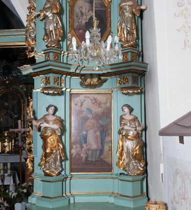 Zdjęcie nr 2: Ołtarz architektoniczny, dwukondygnacyjny, jednoosiowy. Ołtarz drewniany prostopadłościenny z drewnianą mensą i kamiennym portatylem. Dwukondygnacyjne retabulum ustawione na podwójnym i zdwojonym cokole, ujęte parą zdwojonych pilastrów wspierających wyłamujące się belkowanie. W polu głównym umieszczony jest obraz św. Mikołaja w płytkiej wnęce w kształcie stojącego prostokąta. Nad obrazem, w partii fryzu dwie uskrzydlone główki anielskie. Po bokach, na osi podpór, na wysokich cokołach ustawione są rzeźby: po lewej stronie św. Barbary, a po prawej według przekazów w literaturze św. Apolonii. Ponad nimi podwieszone ukośnie fragmenty fryzu ozdobione rozetami na ściankach bocznych, a od spodu szerokimi, zawiniętymi liśćmi akantu. Druga kondygnacja ustawiona na niskim cokole, ujęta parą zdwojonych pilastrów podtrzymujących przerwane belkowanie oraz wolutowy, odwrócony przyczółek, na którego szczycie usadzona jest para aniołków. W polu środkowym w ramie o kształcie stojącego prostokąta i ściętych narożach obraz św. Antoniego Padewskiego. Na osi podpór, na niskich cokołach ozdobionych rozetami ustawione są figury świętych królewiczów, zapewne. Ponad nimi podwieszone fragmenty fryzu, zdobione rozetami oraz z podwieszonymi szyszkami. Na szczycie retabulum niski cokolik, flankowany wolutami, zdobiony na przodzie rozetą z zatkniętym u góry krzyżem zakonu Bożogrobowców. Kondygnacje ujęte z lewej strony uszami: w dolnej suchym akantem, a w górnej akantem przeplecionym wstęgą, zdobioną cekinami. Kolorystyka struktury w kolorze jasnej zieleni, ornamentyka i detal architektoniczny złocone oraz srebrzone.
Napis na portatylu: „1963 d. 26 Jan. / celmus Ac erdemus Julianus / Groblicki, eppus tit philald / phiensis in arabia Auxil. Craco / ven, altare hoc portatile con / secravit et Reliquias Eses. Nn. /  brittcia rp. et florii in eo / inclusit” oraz podpisy piórem niebieskim oraz fragment pieczęci krakowskiej Bazyliki metropolitalnej.