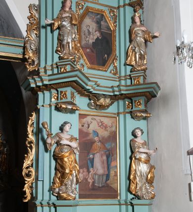 Zdjęcie nr 1: Ołtarz architektoniczny, dwukondygnacyjny, jednoosiowy. Ołtarz drewniany prostopadłościenny z drewnianą mensą i kamiennym portatylem. Dwukondygnacyjne retabulum ustawione na podwójnym i zdwojonym cokole, ujęte parą zdwojonych pilastrów wspierających wyłamujące się belkowanie. W polu głównym umieszczony jest obraz św. Mikołaja w płytkiej wnęce w kształcie stojącego prostokąta. Nad obrazem, w partii fryzu dwie uskrzydlone główki anielskie. Po bokach, na osi podpór, na wysokich cokołach ustawione są rzeźby: po lewej stronie św. Barbary, a po prawej według przekazów w literaturze św. Apolonii. Ponad nimi podwieszone ukośnie fragmenty fryzu ozdobione rozetami na ściankach bocznych, a od spodu szerokimi, zawiniętymi liśćmi akantu. Druga kondygnacja ustawiona na niskim cokole, ujęta parą zdwojonych pilastrów podtrzymujących przerwane belkowanie oraz wolutowy, odwrócony przyczółek, na którego szczycie usadzona jest para aniołków. W polu środkowym w ramie o kształcie stojącego prostokąta i ściętych narożach obraz św. Antoniego Padewskiego. Na osi podpór, na niskich cokołach ozdobionych rozetami ustawione są figury świętych królewiczów, zapewne. Ponad nimi podwieszone fragmenty fryzu, zdobione rozetami oraz z podwieszonymi szyszkami. Na szczycie retabulum niski cokolik, flankowany wolutami, zdobiony na przodzie rozetą z zatkniętym u góry krzyżem zakonu Bożogrobowców. Kondygnacje ujęte z lewej strony uszami: w dolnej suchym akantem, a w górnej akantem przeplecionym wstęgą, zdobioną cekinami. Kolorystyka struktury w kolorze jasnej zieleni, ornamentyka i detal architektoniczny złocone oraz srebrzone.
Napis na portatylu: „1963 d. 26 Jan. / celmus Ac erdemus Julianus / Groblicki, eppus tit philald / phiensis in arabia Auxil. Craco / ven, altare hoc portatile con / secravit et Reliquias Eses. Nn. /  brittcia rp. et florii in eo / inclusit” oraz podpisy piórem niebieskim oraz fragment pieczęci krakowskiej Bazyliki metropolitalnej.