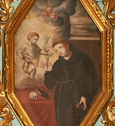 Zdjęcie nr 1: Obraz w kształcie wydłużonego, stojącego ośmioboku z przedstawieniem św. Antoniego, ukazanego w trzech czwartych do wysokości kolan. Święty zwrócony jest delikatnie w prawo, lewą rękę ma opuszczoną w dół, a w prawej ugiętej w łokciu trzyma kwiat lilii. Twarz pełna o delikatnych rysach z małymi oczami, na głowie tonsura. Ubrany jest w habit franciszkański, przewiązany cingulum z różańcem zawieszonym u lewego boku. Po lewej stronie kompozycji znajduje się stolik nakryty czerwonym obrusem, na którym leży czaszka i oparta o nią księga. Nad stolikiem na chmurze obłoków stoi zwrócone trzy czwarte w lewo Dzieciątko w rozświetlonej poświacie, które lewą dłonią chwyta gałązkę lilii, a prawą podtrzymuje płaszcz. Dzieciątko ma krótkie, kędzierzawe włosy. Ubrane jest w szatę, która odsłania nagi tors i nogi, przewieszoną przez ramiona i biegnącą na wysokości bioder. Powyżej na chmurze obłoków trzy uskrzydlone główki aniołków i jedna na skraju obłoków. Całość ukazana we wnętrzu architektonicznym z oknem po prawej stronie. Za oknem widok na port ze statkami i miastem w oddali. Rama drewniana, profilowana, zdobiona liśćmi wawrzynu. 