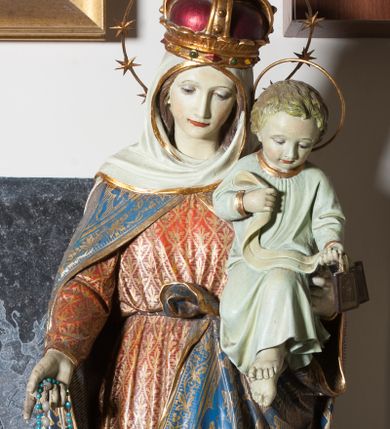 Zdjęcie nr 1: Rzeźba pełnoplastyczna, pełnopostaciowa przedstawiająca Matkę Boską z Dzieciątkiem. Maria ukazana frontalnie w postawie stojącej z Dzieciątkiem na lewym ręku, prawą trzymająca połę płaszcza, głowa delikatnie opuszczona w dół. Twarz owalna o delikatnych rysach, długim nosie i wąskich ustach. Ubrana jest w długą, czerwoną suknię ze złoconym ornamentem geometryczno-roślinnym, przewiązaną w pasie oraz spięty pod szyją, niebieski płaszcz ze złoconym ornamentem roślinnym, na głowie ma biały welon i koronę zamkniętą, a wokół głowy nimb z 12 gwiazd na metalowej obręczy. Na stopach ma buty o spiczastych noskach. Dzieciątko ukazane frontalnie trzymające w dłoniach szkaplerze. Twarz o rysach dziecięcych, włosy jasne i krótkie. Wokół głowy okrągły nimb z metalowej obręczy. Dzieciątko ubrane jest w białą sukienkę ze złoconymi obrzeżami. Karnacje bardzo jasne, blade. Na podstawie, z boku dwie sygnatury z nazwą warsztatu i miejscem wykonania: „Mayer’sche K. Hof-Kunstanstalt”, „Mayer’sche K. Hof-Kunstanstalt [?] / München”. Po lewej nieczytelny znak firmowy.