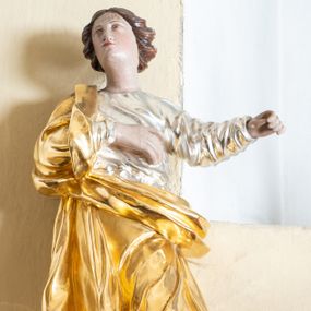 Zdjęcie nr 1: Rzeźba ścięta z tyłu przedstawiająca św. Marię Magdalenę. Święta ukazana w postawie stojącej w delikatnym kontrapoście z prawą dłonią złożoną na piersi i lewą wyciągniętą w bok. Twarz pełna z małymi ustami, długim nosem oraz wąskimi oczami. Włosy ciemne, średniej długości zawinięte do tyłu w bujne loki. 
Ubrana jest w srebrzoną suknię z długimi rękawami oraz złocony płaszcz przewieszony przez prawe ramię i spływający z przodu przez biodra. Na stopach ma brązowe buty. Polichromia w odsłoniętych partiach ciała naturalistyczna. 

