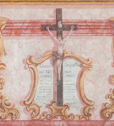 Zdjęcie nr 5: Polichromia ścienna przedstawia ukazany w sposób iluzjonistyczny ołtarz boczny św. Józefa. Mensa sarkofagowa, ozdobiona rocaille’owym kartuszem z napisem: „Dia 22 / July / 1796.”. Nastawa ustawiona na zdwojonym cokole. W górnej partii cokołu trzy rocaille’owe płyciny z modlitwami z kanonu mszy świętej. Na płycinie środkowej: „Gloria Credo in Deo / HOC EST ENIM / CORPUS MEUM”. Na płycinie lewej: „Evange/lium S 90 / IN principca / cruc Verbum, (…)VERBUM / CA(…)FA”. Na płycinie prawej: „Deus (…) / Mc / LAVabo inter / innocentes / manus meas”. Na mensie ołtarzowej na tle kanonu ustawiony jest krucyfiks, a po bokach dwa rokokowe lichtarze. Nastawa ujęta parami pilastrów, ustawionymi przed nimi filarami oraz kolumnami. Kolumny o kręconych trzonach, kapitele fantazyjne. Podpory podtrzymują pełne, przerwane nad polem głównym belkowanie z wolutowymi przyczółkami, na których usadzona jest para aniołków. W polu głównym w ramie w kształcie stojącego prostokąta zamkniętego łukiem wklęsło-wypukłym z uskokami jest namalowany obraz św. Józefa z Dzieciątkiem. Po bokach ołtarza rocaille’owe uszy ze zwisami kwiatowymi. Zwieńczenie w kształcie zbliżonym do stojącego prostokąta o wklęsłych bokach, ujętych spływami wolutowymi, na których w górnej części po bokach znajdują się imposty z usadzonymi na nich dwoma aniołkami. Szczyt zamknięty czterema spiętymi wolutkami, pośrodku krzyż o kształcie krzyża maltańskiego, poniżej podwieszony pas lambrekinu. W polu głównym zwieńczenia w owalnej ramie obraz przedstawiający św. Jana Nepomucena. Zwieńczenie dekorowane zwisami z gałązek różanych. Nastawa marmoryzowana w kolorze jasnoróżowym i jasnoróżowym, trzony kolumn, rama obrazu ze św. Janem Nepomucenem oraz mensa w kolorze jasnoniebieskim, a ornamentyka malowana jest w kolorze złotym. 