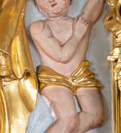 Zdjęcie nr 21: Ołtarz przyścienny, architektoniczny z mensą w formie sarkofagu o wklęsło-wypukłych bokach. W mensie kamienny portatyl. Retabulum jednoosiowe, jednokondygnacyjne ze zwieńczeniem, ustawione na wysokim zdwojonym cokole, zryzalitowanym bo bokach. Nastawa ujęta parą narożnych pilastrów kompozytowych oraz parą kolumn znacznie wysuniętych przed lico ołtarza. Kolumny o kanelowanych trzonach i kompozytowych głowicach podtrzymują faliste belkowanie. Zwieńczenie ujęte po bokach motywami „S” kształtnymi o wolutowo zwiniętych końcach, z których dolne mocno wysunięte do przodu, spoczywają na belkowaniu. Zwieńczenie zamknięte dwoma stykającymi się wolutami. Po bokach retabulum ażurowe uszaki formowane z grzebieni rocaille'owych i motywów „C” kształtnych z rzeźbioną, uskrzydloną główką anielską. 
Pole środkowe w kształcie prostokątnej wnęki z zamknięciem kształtowanym z motywów „C”. We wnęce płaskorzeźba z przedstwieniem św. Mikołaja ujęta podwójną profilowaną ramą. U dołu, po bokach wnęki dwie konsole z ustawionymi pełnoplastycznymi figurami św. Augustyna po lewej oraz św. Marcina (?) po prawej stronie. Ponad kolumnami, po bokach zwieńczenia dwie figury aniołów, powyżej para uskrzydlonych puttów. W zwieńczeniu owalna wnęka z obrazem przedstawiającym św. Sebastiana, ujętym podwójną ramą. 
Ołtarz bogato dekorowany. Mensa zdobiona ornamentem rocaille'owym. Pola cokołów zdobione płycinami kształtowanymi z grzebieni rocaille'owych dekorujących też fryz. Trzony kolumn i pilastrów zdobią podwieszane motywy rocaille'owe przeplatane z gałązkami róż, tworzącymi również rozległy, ażurowy kartusz nad polem środkowym. Boki zwieńczenia ujęte ażurowymi liśćmi akantu. Poniżej wnęki ażurowa, ukośna kratka regencyjna. Boki wnęki i szczyt zwieńczenia dekorowane pełnoplastycznymi rocaille'ami. 
Całość struktury ołtarza pokryta malowaną marmoryzacją w odcieniach zieleni i brązu. Detal architektoniczny złocony, pilastry srebrzone.