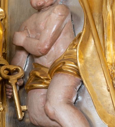 Zdjęcie nr 22: Ołtarz przyścienny, architektoniczny z mensą w formie sarkofagu o wklęsło-wypukłych bokach. W mensie kamienny portatyl. Retabulum jednoosiowe, jednokondygnacyjne ze zwieńczeniem, ustawione na wysokim zdwojonym cokole, zryzalitowanym bo bokach. Nastawa ujęta parą narożnych pilastrów kompozytowych oraz parą kolumn znacznie wysuniętych przed lico ołtarza. Kolumny o kanelowanych trzonach i kompozytowych głowicach podtrzymują faliste belkowanie. Zwieńczenie ujęte po bokach motywami „S” kształtnymi o wolutowo zwiniętych końcach, z których dolne mocno wysunięte do przodu, spoczywają na belkowaniu. Zwieńczenie zamknięte dwoma stykającymi się wolutami. Po bokach retabulum ażurowe uszaki formowane z grzebieni rocaille&#039;owych i motywów „C” kształtnych z rzeźbioną, uskrzydloną główką anielską. 
Pole środkowe w kształcie prostokątnej wnęki z zamknięciem kształtowanym z motywów „C”. We wnęce płaskorzeźba z przedstwieniem św. Mikołaja ujęta podwójną profilowaną ramą. U dołu, po bokach wnęki dwie konsole z ustawionymi pełnoplastycznymi figurami św. Augustyna po lewej oraz św. Marcina (?) po prawej stronie. Ponad kolumnami, po bokach zwieńczenia dwie figury aniołów, powyżej para uskrzydlonych puttów. W zwieńczeniu owalna wnęka z obrazem przedstawiającym św. Sebastiana, ujętym podwójną ramą. 
Ołtarz bogato dekorowany. Mensa zdobiona ornamentem rocaille&#039;owym. Pola cokołów zdobione płycinami kształtowanymi z grzebieni rocaille&#039;owych dekorujących też fryz. Trzony kolumn i pilastrów zdobią podwieszane motywy rocaille&#039;owe przeplatane z gałązkami róż, tworzącymi również rozległy, ażurowy kartusz nad polem środkowym. Boki zwieńczenia ujęte ażurowymi liśćmi akantu. Poniżej wnęki ażurowa, ukośna kratka regencyjna. Boki wnęki i szczyt zwieńczenia dekorowane pełnoplastycznymi rocaille&#039;ami. 
Całość struktury ołtarza pokryta malowaną marmoryzacją w odcieniach zieleni i brązu. Detal architektoniczny złocony, pilastry srebrzone.