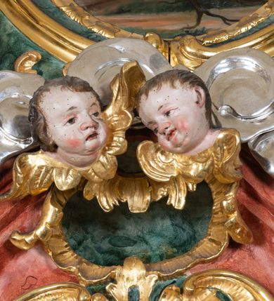 Zdjęcie nr 4: Ołtarz przyścienny, architektoniczny z mensą w formie sarkofagu o wklęsło-wypukłych bokach. W mensie kamienny portatyl. Retabulum jednoosiowe, jednokondygnacyjne ze zwieńczeniem, ustawione na wysokim zdwojonym cokole, zryzalitowanym bo bokach. Nastawa ujęta parą narożnych pilastrów kompozytowych oraz parą kolumn znacznie wysuniętych przed lico ołtarza. Kolumny o kanelowanych trzonach i kompozytowych głowicach podtrzymują faliste belkowanie. Zwieńczenie ujęte po bokach motywami „S” kształtnymi o wolutowo zwiniętych końcach, z których dolne mocno wysunięte do przodu, spoczywają na belkowaniu. Zwieńczenie zamknięte dwoma stykającymi się wolutami. Po bokach retabulum ażurowe uszaki formowane z grzebieni rocaille'owych i motywów „C” kształtnych z rzeźbioną, uskrzydloną główką anielską. 
Pole środkowe w kształcie prostokątnej wnęki z zamknięciem kształtowanym z motywów „C”. We wnęce płaskorzeźba z przedstwieniem św. Mikołaja ujęta podwójną profilowaną ramą. U dołu, po bokach wnęki dwie konsole z ustawionymi pełnoplastycznymi figurami św. Augustyna po lewej oraz św. Marcina (?) po prawej stronie. Ponad kolumnami, po bokach zwieńczenia dwie figury aniołów, powyżej para uskrzydlonych puttów. W zwieńczeniu owalna wnęka z obrazem przedstawiającym św. Sebastiana, ujętym podwójną ramą. 
Ołtarz bogato dekorowany. Mensa zdobiona ornamentem rocaille'owym. Pola cokołów zdobione płycinami kształtowanymi z grzebieni rocaille'owych dekorujących też fryz. Trzony kolumn i pilastrów zdobią podwieszane motywy rocaille'owe przeplatane z gałązkami róż, tworzącymi również rozległy, ażurowy kartusz nad polem środkowym. Boki zwieńczenia ujęte ażurowymi liśćmi akantu. Poniżej wnęki ażurowa, ukośna kratka regencyjna. Boki wnęki i szczyt zwieńczenia dekorowane pełnoplastycznymi rocaille'ami. 
Całość struktury ołtarza pokryta malowaną marmoryzacją w odcieniach zieleni i brązu. Detal architektoniczny złocony, pilastry srebrzone.