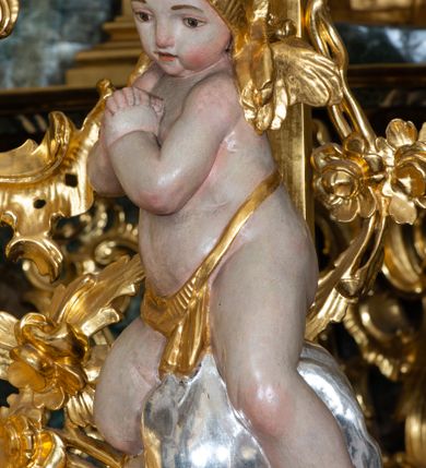 Zdjęcie nr 5: Nastawa ołtarzowa architektoniczna, trójosiowa z bramkami, jednokondygnacyjna ze zwieńczeniem. Ołtarz wysunięty do przodu, drewniany, sarkofagowy, wklęsło-wypukły, zwężający się ku dołowi, na profilowanym cokole, ujęty spływami wolutowymi; dekorowany w narożach palmetami, na froncie rocaille&#039;owy kartusz z malowanymi skrzyżowanymi kluczami w polu. Mensa drewniana z silnie wysuniętą, profilowaną krawędzią, z portatylem z piaskowca. 

Tabernakulum w formie prostopadłościennej skrzynki o wypukłej ściance frontowej, ujęte z przodu ukośnie dostawionymi pilastrami na cokołach z trzonami w formie wolut, dźwigającymi niepełne belkowanie, opasujące je z trzech stron, nad ścianką frontową przyjmujące falistą formę zwieńczoną rocaille&#039;m. Drzwiczki przyjmują kształt stojącego prostokąta zamkniętego łukiem półkolistym nadwieszonym, ujęte profilowaną ramą; w polu płaskorzeźbione przedstawienie kielicha z hostią w glorii na fakturowanym tle. Na belkowaniu, na osi podpór ustawiona jest para rocaille&#039;owych lichtarzy. Tron wystawienia architektoniczny, trójosiowy; oś środkowa ponad tabernakulum w postaci ażurowej niszy z cokołem na pasyjkę, tylna ścianka utworzona z rocaille&#039;u z kłosami zbóż; flankowana pilastrami zwieńczonymi falistym gzymsem, dźwigającymi ażurową, zamkniętą koronę. Podpory przechodzą w spływy wolutowe, ujmujące tabernakulum, na których końcach siedzi para adorujących puttów. Osie boczne są ujęte po bokach pilastrami dźwigającymi imposty podtrzymywane przez rocaille w partii trzonów oraz płonące wazony; pola wypełnione ażurowym rocaille&#039;m i palmetami przechodzącymi w podwójne lichtarze.

Retabulum na planie półowalu, osie boczne ustawione prostopadle do środkowej. Oś środkowa posadowiona na wysokim, dwustrefowym cokole. W pierwszej strefie cokołu prostokątna płycina z napisem: „Z INICJATYWY / KS. PROBOSZCZA ROMANA GORCZYŃSKIEGO / W LATACH 2001 - 2006 / WYKONANO REMONT KOŚCIOŁA I KONSERWACJĘ / WYPOSAŻENIA”. W drugiej strefie cokołu, pośrodku płycina w formie leżącego prostokąta o fantazyjnie wyciętych bokach z malowanym kartuszem herbowym, dzielonym na cztery pola. W lewym górnym polu kartusza umieszczony jest orzeł, poniżej dwójka dzieci w łódce, a po prawej stronie tarczy, w prawym górnym polu dwójka dzieci w łódce, poniżej orzeł. U spodu napis z chronostychem: „EREXIT, AC EXORNAVIT HONORIBVS SANCTI PETRI, / AC PAVLI APOSTOLI ILLVSTRISSIMVS LIBER BAR I WNBS(?) IOANELLY / A TOLVANA PROPPII X I”. Klejnotem jest hełm z pióropuszem zakończony półpostacią rycerza w zbroi, zaś labry mają formę bujnej wici akantowej.  Ryzality cokołów ozdobione są z trzech stron rocaille&#039;owymi płycinami; skrajne konsole rocaille&#039;m i różanymi gałązkami. Oś główna flankowana parą kolumn ustawioną na tle zwielokrotnionych pilastrów. Podpory dźwigają pełne belkowanie, przerwane nad polem środkowym, wyłamane na ich osi oraz przerwany wolutowy przyczółek. W polu środkowym podwójna, profilowana rama w formie stojącego prostokąta zamkniętego łukiem nadwieszonym z uskokami z obrazem św. Piotra i św. Pawła; flankowana przez figury św. Szymona po lewej stronie i św. Judy Tadeusza po prawej, ustawionymi na rocaille&#039;owych wspornikach. Ramy obrazu, trzony wewnętrznych pilastrów i pola za środkową parą figur dekorowane rocaille&#039;m. 

Zwieńczenie w formie zbliżonej do stojącego prostokąta, ujęte spływami wolutowymi, zamknięte falistym gzymsem przechodzącym w antytetycznie zwrócone woluty. Całość zwieńczona gołębicą Ducha Świętego w glorii promienistej. W polu rzeźbiarska grupa Koronacji Marii w glorii promienistej, pośród obłoków i uskrzydlonych główek anielskich. Dwa flankujące grupę putta  na obłokach trzymają banderole z napisem: „FILIA DEI PATRIS” i „MATER DEI FILII”, a kolejne dwa usadzone na szczycie: „VENI CORONABERIS” oraz „VENI SPONSA MEA”. Poniżej zwieńczenia w ażurowym kartuszu znajduje się napis: „QVA E/ST ISTA / QVAE PROGREDI/TUR QVASI AURORA / CONSURGENS / Cant 6.”. Na przyczółku siedzące figury św. Joachima po lewej stronie i św. Józefa po prawej, na gzymsie flankującym pole środkowe dwa putta trzymające słońce i księżyc, na zewnętrznych osiach dwa adorujące anioły. Spływy zwieńczenia dekorowane strzępiastymi liśćmi palmowymi, muszlą i rocaille’m. 

Osie boczne ustawione są na wysokim cokole, od zewnątrz ujęte pilastrami przechodzącymi w woluty, od wewnątrz sąsiadują z osią środkową. Pośrodku bramki z drzwiczkami zakończonymi gzymsem przyjmującym formę cokołu dla figur. Drzwiczki w formie stojącego prostokątna zamkniętego łukiem segmentowym nadwieszonym; osie na skraju ujęte konsolami stanowiącymi cokoły dla podpór. Ryzalit bramek zdobiony płyciną ze strzępiastym grzebieniem; drzwiczki z płyciną z rocaille&#039;m i kwiatowym zwisem na wstążce; powyższy cokół ujęty liśćmi palmowymi i rocaille&#039;m. Kondygnacja flankowana na skraju kolumną ustawioną na tle pilastru, które podtrzymują wyłamany gzyms zakończony wolutami ujmującymi szczyt o falistym przebiegu, na którym ustawiony jest duży płomienisty wazon. W polach ustawione są figury: po lewej się Jakuba Starszego, a po prawej św. Filipa. Na zwieńczeniach usadzone dwie figury aniołów. 

Struktura w całości marmoryzowana w kolorze zielono-brązowym; ornamentyka, kolumny złocone, detale srebrzone. Wszystkie kolumny w jednej trzeciej wysokości przedzielone rocaille’m, a fryz z elementami dekoracji rokokowej. Tabernakulum i tron wystawienia w całości złocone.

