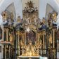 Zdjęcie nr 1: Nastawa ołtarzowa architektoniczna, trójosiowa z bramkami, jednokondygnacyjna ze zwieńczeniem. Ołtarz wysunięty do przodu, drewniany, sarkofagowy, wklęsło-wypukły, zwężający się ku dołowi, na profilowanym cokole, ujęty spływami wolutowymi; dekorowany w narożach palmetami, na froncie rocaille'owy kartusz z malowanymi skrzyżowanymi kluczami w polu. Mensa drewniana z silnie wysuniętą, profilowaną krawędzią, z portatylem z piaskowca. 

Tabernakulum w formie prostopadłościennej skrzynki o wypukłej ściance frontowej, ujęte z przodu ukośnie dostawionymi pilastrami na cokołach z trzonami w formie wolut, dźwigającymi niepełne belkowanie, opasujące je z trzech stron, nad ścianką frontową przyjmujące falistą formę zwieńczoną rocaille'm. Drzwiczki przyjmują kształt stojącego prostokąta zamkniętego łukiem półkolistym nadwieszonym, ujęte profilowaną ramą; w polu płaskorzeźbione przedstawienie kielicha z hostią w glorii na fakturowanym tle. Na belkowaniu, na osi podpór ustawiona jest para rocaille'owych lichtarzy. Tron wystawienia architektoniczny, trójosiowy; oś środkowa ponad tabernakulum w postaci ażurowej niszy z cokołem na pasyjkę, tylna ścianka utworzona z rocaille'u z kłosami zbóż; flankowana pilastrami zwieńczonymi falistym gzymsem, dźwigającymi ażurową, zamkniętą koronę. Podpory przechodzą w spływy wolutowe, ujmujące tabernakulum, na których końcach siedzi para adorujących puttów. Osie boczne są ujęte po bokach pilastrami dźwigającymi imposty podtrzymywane przez rocaille w partii trzonów oraz płonące wazony; pola wypełnione ażurowym rocaille'm i palmetami przechodzącymi w podwójne lichtarze.

Retabulum na planie półowalu, osie boczne ustawione prostopadle do środkowej. Oś środkowa posadowiona na wysokim, dwustrefowym cokole. W pierwszej strefie cokołu prostokątna płycina z napisem: „Z INICJATYWY / KS. PROBOSZCZA ROMANA GORCZYŃSKIEGO / W LATACH 2001 - 2006 / WYKONANO REMONT KOŚCIOŁA I KONSERWACJĘ / WYPOSAŻENIA”. W drugiej strefie cokołu, pośrodku płycina w formie leżącego prostokąta o fantazyjnie wyciętych bokach z malowanym kartuszem herbowym, dzielonym na cztery pola. W lewym górnym polu kartusza umieszczony jest orzeł, poniżej dwójka dzieci w łódce, a po prawej stronie tarczy, w prawym górnym polu dwójka dzieci w łódce, poniżej orzeł. U spodu napis z chronostychem: „EREXIT, AC EXORNAVIT HONORIBVS SANCTI PETRI, / AC PAVLI APOSTOLI ILLVSTRISSIMVS LIBER BAR I WNBS(?) IOANELLY / A TOLVANA PROPPII X I”. Klejnotem jest hełm z pióropuszem zakończony półpostacią rycerza w zbroi, zaś labry mają formę bujnej wici akantowej.  Ryzality cokołów ozdobione są z trzech stron rocaille'owymi płycinami; skrajne konsole rocaille'm i różanymi gałązkami. Oś główna flankowana parą kolumn ustawioną na tle zwielokrotnionych pilastrów. Podpory dźwigają pełne belkowanie, przerwane nad polem środkowym, wyłamane na ich osi oraz przerwany wolutowy przyczółek. W polu środkowym podwójna, profilowana rama w formie stojącego prostokąta zamkniętego łukiem nadwieszonym z uskokami z obrazem św. Piotra i św. Pawła; flankowana przez figury św. Szymona po lewej stronie i św. Judy Tadeusza po prawej, ustawionymi na rocaille'owych wspornikach. Ramy obrazu, trzony wewnętrznych pilastrów i pola za środkową parą figur dekorowane rocaille'm. 

Zwieńczenie w formie zbliżonej do stojącego prostokąta, ujęte spływami wolutowymi, zamknięte falistym gzymsem przechodzącym w antytetycznie zwrócone woluty. Całość zwieńczona gołębicą Ducha Świętego w glorii promienistej. W polu rzeźbiarska grupa Koronacji Marii w glorii promienistej, pośród obłoków i uskrzydlonych główek anielskich. Dwa flankujące grupę putta  na obłokach trzymają banderole z napisem: „FILIA DEI PATRIS” i „MATER DEI FILII”, a kolejne dwa usadzone na szczycie: „VENI CORONABERIS” oraz „VENI SPONSA MEA”. Poniżej zwieńczenia w ażurowym kartuszu znajduje się napis: „QVA E/ST ISTA / QVAE PROGREDI/TUR QVASI AURORA / CONSURGENS / Cant 6.”. Na przyczółku siedzące figury św. Joachima po lewej stronie i św. Józefa po prawej, na gzymsie flankującym pole środkowe dwa putta trzymające słońce i księżyc, na zewnętrznych osiach dwa adorujące anioły. Spływy zwieńczenia dekorowane strzępiastymi liśćmi palmowymi, muszlą i rocaille’m. 

Osie boczne ustawione są na wysokim cokole, od zewnątrz ujęte pilastrami przechodzącymi w woluty, od wewnątrz sąsiadują z osią środkową. Pośrodku bramki z drzwiczkami zakończonymi gzymsem przyjmującym formę cokołu dla figur. Drzwiczki w formie stojącego prostokątna zamkniętego łukiem segmentowym nadwieszonym; osie na skraju ujęte konsolami stanowiącymi cokoły dla podpór. Ryzalit bramek zdobiony płyciną ze strzępiastym grzebieniem; drzwiczki z płyciną z rocaille'm i kwiatowym zwisem na wstążce; powyższy cokół ujęty liśćmi palmowymi i rocaille'm. Kondygnacja flankowana na skraju kolumną ustawioną na tle pilastru, które podtrzymują wyłamany gzyms zakończony wolutami ujmującymi szczyt o falistym przebiegu, na którym ustawiony jest duży płomienisty wazon. W polach ustawione są figury: po lewej się Jakuba Starszego, a po prawej św. Filipa. Na zwieńczeniach usadzone dwie figury aniołów. 

Struktura w całości marmoryzowana w kolorze zielono-brązowym; ornamentyka, kolumny złocone, detale srebrzone. Wszystkie kolumny w jednej trzeciej wysokości przedzielone rocaille’m, a fryz z elementami dekoracji rokokowej. Tabernakulum i tron wystawienia w całości złocone.

