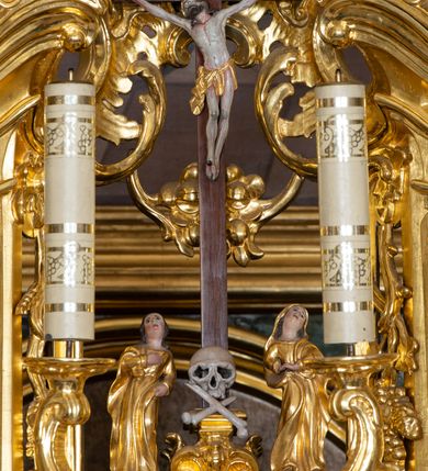 Zdjęcie nr 3: Nastawa ołtarzowa architektoniczna, trójosiowa z bramkami, jednokondygnacyjna ze zwieńczeniem. Ołtarz wysunięty do przodu, drewniany, sarkofagowy, wklęsło-wypukły, zwężający się ku dołowi, na profilowanym cokole, ujęty spływami wolutowymi; dekorowany w narożach palmetami, na froncie rocaille&#039;owy kartusz z malowanymi skrzyżowanymi kluczami w polu. Mensa drewniana z silnie wysuniętą, profilowaną krawędzią, z portatylem z piaskowca. 

Tabernakulum w formie prostopadłościennej skrzynki o wypukłej ściance frontowej, ujęte z przodu ukośnie dostawionymi pilastrami na cokołach z trzonami w formie wolut, dźwigającymi niepełne belkowanie, opasujące je z trzech stron, nad ścianką frontową przyjmujące falistą formę zwieńczoną rocaille&#039;m. Drzwiczki przyjmują kształt stojącego prostokąta zamkniętego łukiem półkolistym nadwieszonym, ujęte profilowaną ramą; w polu płaskorzeźbione przedstawienie kielicha z hostią w glorii na fakturowanym tle. Na belkowaniu, na osi podpór ustawiona jest para rocaille&#039;owych lichtarzy. Tron wystawienia architektoniczny, trójosiowy; oś środkowa ponad tabernakulum w postaci ażurowej niszy z cokołem na pasyjkę, tylna ścianka utworzona z rocaille&#039;u z kłosami zbóż; flankowana pilastrami zwieńczonymi falistym gzymsem, dźwigającymi ażurową, zamkniętą koronę. Podpory przechodzą w spływy wolutowe, ujmujące tabernakulum, na których końcach siedzi para adorujących puttów. Osie boczne są ujęte po bokach pilastrami dźwigającymi imposty podtrzymywane przez rocaille w partii trzonów oraz płonące wazony; pola wypełnione ażurowym rocaille&#039;m i palmetami przechodzącymi w podwójne lichtarze.

Retabulum na planie półowalu, osie boczne ustawione prostopadle do środkowej. Oś środkowa posadowiona na wysokim, dwustrefowym cokole. W pierwszej strefie cokołu prostokątna płycina z napisem: „Z INICJATYWY / KS. PROBOSZCZA ROMANA GORCZYŃSKIEGO / W LATACH 2001 - 2006 / WYKONANO REMONT KOŚCIOŁA I KONSERWACJĘ / WYPOSAŻENIA”. W drugiej strefie cokołu, pośrodku płycina w formie leżącego prostokąta o fantazyjnie wyciętych bokach z malowanym kartuszem herbowym, dzielonym na cztery pola. W lewym górnym polu kartusza umieszczony jest orzeł, poniżej dwójka dzieci w łódce, a po prawej stronie tarczy, w prawym górnym polu dwójka dzieci w łódce, poniżej orzeł. U spodu napis z chronostychem: „EREXIT, AC EXORNAVIT HONORIBVS SANCTI PETRI, / AC PAVLI APOSTOLI ILLVSTRISSIMVS LIBER BAR I WNBS(?) IOANELLY / A TOLVANA PROPPII X I”. Klejnotem jest hełm z pióropuszem zakończony półpostacią rycerza w zbroi, zaś labry mają formę bujnej wici akantowej.  Ryzality cokołów ozdobione są z trzech stron rocaille&#039;owymi płycinami; skrajne konsole rocaille&#039;m i różanymi gałązkami. Oś główna flankowana parą kolumn ustawioną na tle zwielokrotnionych pilastrów. Podpory dźwigają pełne belkowanie, przerwane nad polem środkowym, wyłamane na ich osi oraz przerwany wolutowy przyczółek. W polu środkowym podwójna, profilowana rama w formie stojącego prostokąta zamkniętego łukiem nadwieszonym z uskokami z obrazem św. Piotra i św. Pawła; flankowana przez figury św. Szymona po lewej stronie i św. Judy Tadeusza po prawej, ustawionymi na rocaille&#039;owych wspornikach. Ramy obrazu, trzony wewnętrznych pilastrów i pola za środkową parą figur dekorowane rocaille&#039;m. 

Zwieńczenie w formie zbliżonej do stojącego prostokąta, ujęte spływami wolutowymi, zamknięte falistym gzymsem przechodzącym w antytetycznie zwrócone woluty. Całość zwieńczona gołębicą Ducha Świętego w glorii promienistej. W polu rzeźbiarska grupa Koronacji Marii w glorii promienistej, pośród obłoków i uskrzydlonych główek anielskich. Dwa flankujące grupę putta  na obłokach trzymają banderole z napisem: „FILIA DEI PATRIS” i „MATER DEI FILII”, a kolejne dwa usadzone na szczycie: „VENI CORONABERIS” oraz „VENI SPONSA MEA”. Poniżej zwieńczenia w ażurowym kartuszu znajduje się napis: „QVA E/ST ISTA / QVAE PROGREDI/TUR QVASI AURORA / CONSURGENS / Cant 6.”. Na przyczółku siedzące figury św. Joachima po lewej stronie i św. Józefa po prawej, na gzymsie flankującym pole środkowe dwa putta trzymające słońce i księżyc, na zewnętrznych osiach dwa adorujące anioły. Spływy zwieńczenia dekorowane strzępiastymi liśćmi palmowymi, muszlą i rocaille’m. 

Osie boczne ustawione są na wysokim cokole, od zewnątrz ujęte pilastrami przechodzącymi w woluty, od wewnątrz sąsiadują z osią środkową. Pośrodku bramki z drzwiczkami zakończonymi gzymsem przyjmującym formę cokołu dla figur. Drzwiczki w formie stojącego prostokątna zamkniętego łukiem segmentowym nadwieszonym; osie na skraju ujęte konsolami stanowiącymi cokoły dla podpór. Ryzalit bramek zdobiony płyciną ze strzępiastym grzebieniem; drzwiczki z płyciną z rocaille&#039;m i kwiatowym zwisem na wstążce; powyższy cokół ujęty liśćmi palmowymi i rocaille&#039;m. Kondygnacja flankowana na skraju kolumną ustawioną na tle pilastru, które podtrzymują wyłamany gzyms zakończony wolutami ujmującymi szczyt o falistym przebiegu, na którym ustawiony jest duży płomienisty wazon. W polach ustawione są figury: po lewej się Jakuba Starszego, a po prawej św. Filipa. Na zwieńczeniach usadzone dwie figury aniołów. 

Struktura w całości marmoryzowana w kolorze zielono-brązowym; ornamentyka, kolumny złocone, detale srebrzone. Wszystkie kolumny w jednej trzeciej wysokości przedzielone rocaille’m, a fryz z elementami dekoracji rokokowej. Tabernakulum i tron wystawienia w całości złocone.

