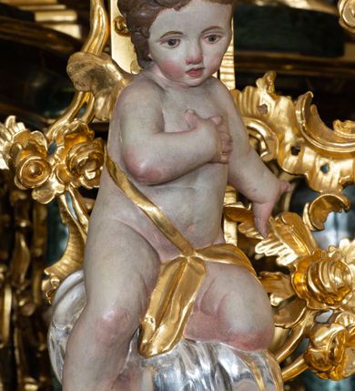 Zdjęcie nr 4: Nastawa ołtarzowa architektoniczna, trójosiowa z bramkami, jednokondygnacyjna ze zwieńczeniem. Ołtarz wysunięty do przodu, drewniany, sarkofagowy, wklęsło-wypukły, zwężający się ku dołowi, na profilowanym cokole, ujęty spływami wolutowymi; dekorowany w narożach palmetami, na froncie rocaille&#039;owy kartusz z malowanymi skrzyżowanymi kluczami w polu. Mensa drewniana z silnie wysuniętą, profilowaną krawędzią, z portatylem z piaskowca. 

Tabernakulum w formie prostopadłościennej skrzynki o wypukłej ściance frontowej, ujęte z przodu ukośnie dostawionymi pilastrami na cokołach z trzonami w formie wolut, dźwigającymi niepełne belkowanie, opasujące je z trzech stron, nad ścianką frontową przyjmujące falistą formę zwieńczoną rocaille&#039;m. Drzwiczki przyjmują kształt stojącego prostokąta zamkniętego łukiem półkolistym nadwieszonym, ujęte profilowaną ramą; w polu płaskorzeźbione przedstawienie kielicha z hostią w glorii na fakturowanym tle. Na belkowaniu, na osi podpór ustawiona jest para rocaille&#039;owych lichtarzy. Tron wystawienia architektoniczny, trójosiowy; oś środkowa ponad tabernakulum w postaci ażurowej niszy z cokołem na pasyjkę, tylna ścianka utworzona z rocaille&#039;u z kłosami zbóż; flankowana pilastrami zwieńczonymi falistym gzymsem, dźwigającymi ażurową, zamkniętą koronę. Podpory przechodzą w spływy wolutowe, ujmujące tabernakulum, na których końcach siedzi para adorujących puttów. Osie boczne są ujęte po bokach pilastrami dźwigającymi imposty podtrzymywane przez rocaille w partii trzonów oraz płonące wazony; pola wypełnione ażurowym rocaille&#039;m i palmetami przechodzącymi w podwójne lichtarze.

Retabulum na planie półowalu, osie boczne ustawione prostopadle do środkowej. Oś środkowa posadowiona na wysokim, dwustrefowym cokole. W pierwszej strefie cokołu prostokątna płycina z napisem: „Z INICJATYWY / KS. PROBOSZCZA ROMANA GORCZYŃSKIEGO / W LATACH 2001 - 2006 / WYKONANO REMONT KOŚCIOŁA I KONSERWACJĘ / WYPOSAŻENIA”. W drugiej strefie cokołu, pośrodku płycina w formie leżącego prostokąta o fantazyjnie wyciętych bokach z malowanym kartuszem herbowym, dzielonym na cztery pola. W lewym górnym polu kartusza umieszczony jest orzeł, poniżej dwójka dzieci w łódce, a po prawej stronie tarczy, w prawym górnym polu dwójka dzieci w łódce, poniżej orzeł. U spodu napis z chronostychem: „EREXIT, AC EXORNAVIT HONORIBVS SANCTI PETRI, / AC PAVLI APOSTOLI ILLVSTRISSIMVS LIBER BAR I WNBS(?) IOANELLY / A TOLVANA PROPPII X I”. Klejnotem jest hełm z pióropuszem zakończony półpostacią rycerza w zbroi, zaś labry mają formę bujnej wici akantowej.  Ryzality cokołów ozdobione są z trzech stron rocaille&#039;owymi płycinami; skrajne konsole rocaille&#039;m i różanymi gałązkami. Oś główna flankowana parą kolumn ustawioną na tle zwielokrotnionych pilastrów. Podpory dźwigają pełne belkowanie, przerwane nad polem środkowym, wyłamane na ich osi oraz przerwany wolutowy przyczółek. W polu środkowym podwójna, profilowana rama w formie stojącego prostokąta zamkniętego łukiem nadwieszonym z uskokami z obrazem św. Piotra i św. Pawła; flankowana przez figury św. Szymona po lewej stronie i św. Judy Tadeusza po prawej, ustawionymi na rocaille&#039;owych wspornikach. Ramy obrazu, trzony wewnętrznych pilastrów i pola za środkową parą figur dekorowane rocaille&#039;m. 

Zwieńczenie w formie zbliżonej do stojącego prostokąta, ujęte spływami wolutowymi, zamknięte falistym gzymsem przechodzącym w antytetycznie zwrócone woluty. Całość zwieńczona gołębicą Ducha Świętego w glorii promienistej. W polu rzeźbiarska grupa Koronacji Marii w glorii promienistej, pośród obłoków i uskrzydlonych główek anielskich. Dwa flankujące grupę putta  na obłokach trzymają banderole z napisem: „FILIA DEI PATRIS” i „MATER DEI FILII”, a kolejne dwa usadzone na szczycie: „VENI CORONABERIS” oraz „VENI SPONSA MEA”. Poniżej zwieńczenia w ażurowym kartuszu znajduje się napis: „QVA E/ST ISTA / QVAE PROGREDI/TUR QVASI AURORA / CONSURGENS / Cant 6.”. Na przyczółku siedzące figury św. Joachima po lewej stronie i św. Józefa po prawej, na gzymsie flankującym pole środkowe dwa putta trzymające słońce i księżyc, na zewnętrznych osiach dwa adorujące anioły. Spływy zwieńczenia dekorowane strzępiastymi liśćmi palmowymi, muszlą i rocaille’m. 

Osie boczne ustawione są na wysokim cokole, od zewnątrz ujęte pilastrami przechodzącymi w woluty, od wewnątrz sąsiadują z osią środkową. Pośrodku bramki z drzwiczkami zakończonymi gzymsem przyjmującym formę cokołu dla figur. Drzwiczki w formie stojącego prostokątna zamkniętego łukiem segmentowym nadwieszonym; osie na skraju ujęte konsolami stanowiącymi cokoły dla podpór. Ryzalit bramek zdobiony płyciną ze strzępiastym grzebieniem; drzwiczki z płyciną z rocaille&#039;m i kwiatowym zwisem na wstążce; powyższy cokół ujęty liśćmi palmowymi i rocaille&#039;m. Kondygnacja flankowana na skraju kolumną ustawioną na tle pilastru, które podtrzymują wyłamany gzyms zakończony wolutami ujmującymi szczyt o falistym przebiegu, na którym ustawiony jest duży płomienisty wazon. W polach ustawione są figury: po lewej się Jakuba Starszego, a po prawej św. Filipa. Na zwieńczeniach usadzone dwie figury aniołów. 

Struktura w całości marmoryzowana w kolorze zielono-brązowym; ornamentyka, kolumny złocone, detale srebrzone. Wszystkie kolumny w jednej trzeciej wysokości przedzielone rocaille’m, a fryz z elementami dekoracji rokokowej. Tabernakulum i tron wystawienia w całości złocone.

