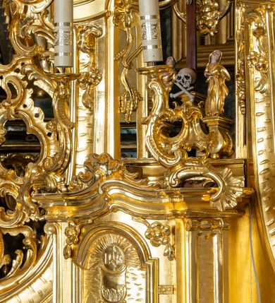 Zdjęcie nr 40: Nastawa ołtarzowa architektoniczna, trójosiowa z bramkami, jednokondygnacyjna ze zwieńczeniem. Ołtarz wysunięty do przodu, drewniany, sarkofagowy, wklęsło-wypukły, zwężający się ku dołowi, na profilowanym cokole, ujęty spływami wolutowymi; dekorowany w narożach palmetami, na froncie rocaille'owy kartusz z malowanymi skrzyżowanymi kluczami w polu. Mensa drewniana z silnie wysuniętą, profilowaną krawędzią, z portatylem z piaskowca. 

Tabernakulum w formie prostopadłościennej skrzynki o wypukłej ściance frontowej, ujęte z przodu ukośnie dostawionymi pilastrami na cokołach z trzonami w formie wolut, dźwigającymi niepełne belkowanie, opasujące je z trzech stron, nad ścianką frontową przyjmujące falistą formę zwieńczoną rocaille'm. Drzwiczki przyjmują kształt stojącego prostokąta zamkniętego łukiem półkolistym nadwieszonym, ujęte profilowaną ramą; w polu płaskorzeźbione przedstawienie kielicha z hostią w glorii na fakturowanym tle. Na belkowaniu, na osi podpór ustawiona jest para rocaille'owych lichtarzy. Tron wystawienia architektoniczny, trójosiowy; oś środkowa ponad tabernakulum w postaci ażurowej niszy z cokołem na pasyjkę, tylna ścianka utworzona z rocaille'u z kłosami zbóż; flankowana pilastrami zwieńczonymi falistym gzymsem, dźwigającymi ażurową, zamkniętą koronę. Podpory przechodzą w spływy wolutowe, ujmujące tabernakulum, na których końcach siedzi para adorujących puttów. Osie boczne są ujęte po bokach pilastrami dźwigającymi imposty podtrzymywane przez rocaille w partii trzonów oraz płonące wazony; pola wypełnione ażurowym rocaille'm i palmetami przechodzącymi w podwójne lichtarze.

Retabulum na planie półowalu, osie boczne ustawione prostopadle do środkowej. Oś środkowa posadowiona na wysokim, dwustrefowym cokole. W pierwszej strefie cokołu prostokątna płycina z napisem: „Z INICJATYWY / KS. PROBOSZCZA ROMANA GORCZYŃSKIEGO / W LATACH 2001 - 2006 / WYKONANO REMONT KOŚCIOŁA I KONSERWACJĘ / WYPOSAŻENIA”. W drugiej strefie cokołu, pośrodku płycina w formie leżącego prostokąta o fantazyjnie wyciętych bokach z malowanym kartuszem herbowym, dzielonym na cztery pola. W lewym górnym polu kartusza umieszczony jest orzeł, poniżej dwójka dzieci w łódce, a po prawej stronie tarczy, w prawym górnym polu dwójka dzieci w łódce, poniżej orzeł. U spodu napis z chronostychem: „EREXIT, AC EXORNAVIT HONORIBVS SANCTI PETRI, / AC PAVLI APOSTOLI ILLVSTRISSIMVS LIBER BAR I WNBS(?) IOANELLY / A TOLVANA PROPPII X I”. Klejnotem jest hełm z pióropuszem zakończony półpostacią rycerza w zbroi, zaś labry mają formę bujnej wici akantowej.  Ryzality cokołów ozdobione są z trzech stron rocaille'owymi płycinami; skrajne konsole rocaille'm i różanymi gałązkami. Oś główna flankowana parą kolumn ustawioną na tle zwielokrotnionych pilastrów. Podpory dźwigają pełne belkowanie, przerwane nad polem środkowym, wyłamane na ich osi oraz przerwany wolutowy przyczółek. W polu środkowym podwójna, profilowana rama w formie stojącego prostokąta zamkniętego łukiem nadwieszonym z uskokami z obrazem św. Piotra i św. Pawła; flankowana przez figury św. Szymona po lewej stronie i św. Judy Tadeusza po prawej, ustawionymi na rocaille'owych wspornikach. Ramy obrazu, trzony wewnętrznych pilastrów i pola za środkową parą figur dekorowane rocaille'm. 

Zwieńczenie w formie zbliżonej do stojącego prostokąta, ujęte spływami wolutowymi, zamknięte falistym gzymsem przechodzącym w antytetycznie zwrócone woluty. Całość zwieńczona gołębicą Ducha Świętego w glorii promienistej. W polu rzeźbiarska grupa Koronacji Marii w glorii promienistej, pośród obłoków i uskrzydlonych główek anielskich. Dwa flankujące grupę putta  na obłokach trzymają banderole z napisem: „FILIA DEI PATRIS” i „MATER DEI FILII”, a kolejne dwa usadzone na szczycie: „VENI CORONABERIS” oraz „VENI SPONSA MEA”. Poniżej zwieńczenia w ażurowym kartuszu znajduje się napis: „QVA E/ST ISTA / QVAE PROGREDI/TUR QVASI AURORA / CONSURGENS / Cant 6.”. Na przyczółku siedzące figury św. Joachima po lewej stronie i św. Józefa po prawej, na gzymsie flankującym pole środkowe dwa putta trzymające słońce i księżyc, na zewnętrznych osiach dwa adorujące anioły. Spływy zwieńczenia dekorowane strzępiastymi liśćmi palmowymi, muszlą i rocaille’m. 

Osie boczne ustawione są na wysokim cokole, od zewnątrz ujęte pilastrami przechodzącymi w woluty, od wewnątrz sąsiadują z osią środkową. Pośrodku bramki z drzwiczkami zakończonymi gzymsem przyjmującym formę cokołu dla figur. Drzwiczki w formie stojącego prostokątna zamkniętego łukiem segmentowym nadwieszonym; osie na skraju ujęte konsolami stanowiącymi cokoły dla podpór. Ryzalit bramek zdobiony płyciną ze strzępiastym grzebieniem; drzwiczki z płyciną z rocaille'm i kwiatowym zwisem na wstążce; powyższy cokół ujęty liśćmi palmowymi i rocaille'm. Kondygnacja flankowana na skraju kolumną ustawioną na tle pilastru, które podtrzymują wyłamany gzyms zakończony wolutami ujmującymi szczyt o falistym przebiegu, na którym ustawiony jest duży płomienisty wazon. W polach ustawione są figury: po lewej się Jakuba Starszego, a po prawej św. Filipa. Na zwieńczeniach usadzone dwie figury aniołów. 

Struktura w całości marmoryzowana w kolorze zielono-brązowym; ornamentyka, kolumny złocone, detale srebrzone. Wszystkie kolumny w jednej trzeciej wysokości przedzielone rocaille’m, a fryz z elementami dekoracji rokokowej. Tabernakulum i tron wystawienia w całości złocone.

