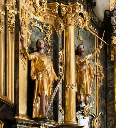 Zdjęcie nr 21: Nastawa ołtarzowa architektoniczna, trójosiowa z bramkami, jednokondygnacyjna ze zwieńczeniem. Ołtarz wysunięty do przodu, drewniany, sarkofagowy, wklęsło-wypukły, zwężający się ku dołowi, na profilowanym cokole, ujęty spływami wolutowymi; dekorowany w narożach palmetami, na froncie rocaille'owy kartusz z malowanymi skrzyżowanymi kluczami w polu. Mensa drewniana z silnie wysuniętą, profilowaną krawędzią, z portatylem z piaskowca. 

Tabernakulum w formie prostopadłościennej skrzynki o wypukłej ściance frontowej, ujęte z przodu ukośnie dostawionymi pilastrami na cokołach z trzonami w formie wolut, dźwigającymi niepełne belkowanie, opasujące je z trzech stron, nad ścianką frontową przyjmujące falistą formę zwieńczoną rocaille'm. Drzwiczki przyjmują kształt stojącego prostokąta zamkniętego łukiem półkolistym nadwieszonym, ujęte profilowaną ramą; w polu płaskorzeźbione przedstawienie kielicha z hostią w glorii na fakturowanym tle. Na belkowaniu, na osi podpór ustawiona jest para rocaille'owych lichtarzy. Tron wystawienia architektoniczny, trójosiowy; oś środkowa ponad tabernakulum w postaci ażurowej niszy z cokołem na pasyjkę, tylna ścianka utworzona z rocaille'u z kłosami zbóż; flankowana pilastrami zwieńczonymi falistym gzymsem, dźwigającymi ażurową, zamkniętą koronę. Podpory przechodzą w spływy wolutowe, ujmujące tabernakulum, na których końcach siedzi para adorujących puttów. Osie boczne są ujęte po bokach pilastrami dźwigającymi imposty podtrzymywane przez rocaille w partii trzonów oraz płonące wazony; pola wypełnione ażurowym rocaille'm i palmetami przechodzącymi w podwójne lichtarze.

Retabulum na planie półowalu, osie boczne ustawione prostopadle do środkowej. Oś środkowa posadowiona na wysokim, dwustrefowym cokole. W pierwszej strefie cokołu prostokątna płycina z napisem: „Z INICJATYWY / KS. PROBOSZCZA ROMANA GORCZYŃSKIEGO / W LATACH 2001 - 2006 / WYKONANO REMONT KOŚCIOŁA I KONSERWACJĘ / WYPOSAŻENIA”. W drugiej strefie cokołu, pośrodku płycina w formie leżącego prostokąta o fantazyjnie wyciętych bokach z malowanym kartuszem herbowym, dzielonym na cztery pola. W lewym górnym polu kartusza umieszczony jest orzeł, poniżej dwójka dzieci w łódce, a po prawej stronie tarczy, w prawym górnym polu dwójka dzieci w łódce, poniżej orzeł. U spodu napis z chronostychem: „EREXIT, AC EXORNAVIT HONORIBVS SANCTI PETRI, / AC PAVLI APOSTOLI ILLVSTRISSIMVS LIBER BAR I WNBS(?) IOANELLY / A TOLVANA PROPPII X I”. Klejnotem jest hełm z pióropuszem zakończony półpostacią rycerza w zbroi, zaś labry mają formę bujnej wici akantowej.  Ryzality cokołów ozdobione są z trzech stron rocaille'owymi płycinami; skrajne konsole rocaille'm i różanymi gałązkami. Oś główna flankowana parą kolumn ustawioną na tle zwielokrotnionych pilastrów. Podpory dźwigają pełne belkowanie, przerwane nad polem środkowym, wyłamane na ich osi oraz przerwany wolutowy przyczółek. W polu środkowym podwójna, profilowana rama w formie stojącego prostokąta zamkniętego łukiem nadwieszonym z uskokami z obrazem św. Piotra i św. Pawła; flankowana przez figury św. Szymona po lewej stronie i św. Judy Tadeusza po prawej, ustawionymi na rocaille'owych wspornikach. Ramy obrazu, trzony wewnętrznych pilastrów i pola za środkową parą figur dekorowane rocaille'm. 

Zwieńczenie w formie zbliżonej do stojącego prostokąta, ujęte spływami wolutowymi, zamknięte falistym gzymsem przechodzącym w antytetycznie zwrócone woluty. Całość zwieńczona gołębicą Ducha Świętego w glorii promienistej. W polu rzeźbiarska grupa Koronacji Marii w glorii promienistej, pośród obłoków i uskrzydlonych główek anielskich. Dwa flankujące grupę putta  na obłokach trzymają banderole z napisem: „FILIA DEI PATRIS” i „MATER DEI FILII”, a kolejne dwa usadzone na szczycie: „VENI CORONABERIS” oraz „VENI SPONSA MEA”. Poniżej zwieńczenia w ażurowym kartuszu znajduje się napis: „QVA E/ST ISTA / QVAE PROGREDI/TUR QVASI AURORA / CONSURGENS / Cant 6.”. Na przyczółku siedzące figury św. Joachima po lewej stronie i św. Józefa po prawej, na gzymsie flankującym pole środkowe dwa putta trzymające słońce i księżyc, na zewnętrznych osiach dwa adorujące anioły. Spływy zwieńczenia dekorowane strzępiastymi liśćmi palmowymi, muszlą i rocaille’m. 

Osie boczne ustawione są na wysokim cokole, od zewnątrz ujęte pilastrami przechodzącymi w woluty, od wewnątrz sąsiadują z osią środkową. Pośrodku bramki z drzwiczkami zakończonymi gzymsem przyjmującym formę cokołu dla figur. Drzwiczki w formie stojącego prostokątna zamkniętego łukiem segmentowym nadwieszonym; osie na skraju ujęte konsolami stanowiącymi cokoły dla podpór. Ryzalit bramek zdobiony płyciną ze strzępiastym grzebieniem; drzwiczki z płyciną z rocaille'm i kwiatowym zwisem na wstążce; powyższy cokół ujęty liśćmi palmowymi i rocaille'm. Kondygnacja flankowana na skraju kolumną ustawioną na tle pilastru, które podtrzymują wyłamany gzyms zakończony wolutami ujmującymi szczyt o falistym przebiegu, na którym ustawiony jest duży płomienisty wazon. W polach ustawione są figury: po lewej się Jakuba Starszego, a po prawej św. Filipa. Na zwieńczeniach usadzone dwie figury aniołów. 

Struktura w całości marmoryzowana w kolorze zielono-brązowym; ornamentyka, kolumny złocone, detale srebrzone. Wszystkie kolumny w jednej trzeciej wysokości przedzielone rocaille’m, a fryz z elementami dekoracji rokokowej. Tabernakulum i tron wystawienia w całości złocone.

