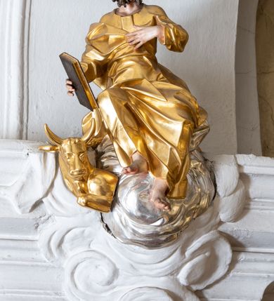 Zdjęcie nr 31: Nastawa ołtarzowa architektoniczna, trójosiowa z bramkami, jednokondygnacyjna ze zwieńczeniem. Ołtarz wysunięty do przodu, drewniany, sarkofagowy, wklęsło-wypukły, zwężający się ku dołowi, na profilowanym cokole, ujęty spływami wolutowymi; dekorowany w narożach palmetami, na froncie rocaille&#039;owy kartusz z malowanymi skrzyżowanymi kluczami w polu. Mensa drewniana z silnie wysuniętą, profilowaną krawędzią, z portatylem z piaskowca. 

Tabernakulum w formie prostopadłościennej skrzynki o wypukłej ściance frontowej, ujęte z przodu ukośnie dostawionymi pilastrami na cokołach z trzonami w formie wolut, dźwigającymi niepełne belkowanie, opasujące je z trzech stron, nad ścianką frontową przyjmujące falistą formę zwieńczoną rocaille&#039;m. Drzwiczki przyjmują kształt stojącego prostokąta zamkniętego łukiem półkolistym nadwieszonym, ujęte profilowaną ramą; w polu płaskorzeźbione przedstawienie kielicha z hostią w glorii na fakturowanym tle. Na belkowaniu, na osi podpór ustawiona jest para rocaille&#039;owych lichtarzy. Tron wystawienia architektoniczny, trójosiowy; oś środkowa ponad tabernakulum w postaci ażurowej niszy z cokołem na pasyjkę, tylna ścianka utworzona z rocaille&#039;u z kłosami zbóż; flankowana pilastrami zwieńczonymi falistym gzymsem, dźwigającymi ażurową, zamkniętą koronę. Podpory przechodzą w spływy wolutowe, ujmujące tabernakulum, na których końcach siedzi para adorujących puttów. Osie boczne są ujęte po bokach pilastrami dźwigającymi imposty podtrzymywane przez rocaille w partii trzonów oraz płonące wazony; pola wypełnione ażurowym rocaille&#039;m i palmetami przechodzącymi w podwójne lichtarze.

Retabulum na planie półowalu, osie boczne ustawione prostopadle do środkowej. Oś środkowa posadowiona na wysokim, dwustrefowym cokole. W pierwszej strefie cokołu prostokątna płycina z napisem: „Z INICJATYWY / KS. PROBOSZCZA ROMANA GORCZYŃSKIEGO / W LATACH 2001 - 2006 / WYKONANO REMONT KOŚCIOŁA I KONSERWACJĘ / WYPOSAŻENIA”. W drugiej strefie cokołu, pośrodku płycina w formie leżącego prostokąta o fantazyjnie wyciętych bokach z malowanym kartuszem herbowym, dzielonym na cztery pola. W lewym górnym polu kartusza umieszczony jest orzeł, poniżej dwójka dzieci w łódce, a po prawej stronie tarczy, w prawym górnym polu dwójka dzieci w łódce, poniżej orzeł. U spodu napis z chronostychem: „EREXIT, AC EXORNAVIT HONORIBVS SANCTI PETRI, / AC PAVLI APOSTOLI ILLVSTRISSIMVS LIBER BAR I WNBS(?) IOANELLY / A TOLVANA PROPPII X I”. Klejnotem jest hełm z pióropuszem zakończony półpostacią rycerza w zbroi, zaś labry mają formę bujnej wici akantowej.  Ryzality cokołów ozdobione są z trzech stron rocaille&#039;owymi płycinami; skrajne konsole rocaille&#039;m i różanymi gałązkami. Oś główna flankowana parą kolumn ustawioną na tle zwielokrotnionych pilastrów. Podpory dźwigają pełne belkowanie, przerwane nad polem środkowym, wyłamane na ich osi oraz przerwany wolutowy przyczółek. W polu środkowym podwójna, profilowana rama w formie stojącego prostokąta zamkniętego łukiem nadwieszonym z uskokami z obrazem św. Piotra i św. Pawła; flankowana przez figury św. Szymona po lewej stronie i św. Judy Tadeusza po prawej, ustawionymi na rocaille&#039;owych wspornikach. Ramy obrazu, trzony wewnętrznych pilastrów i pola za środkową parą figur dekorowane rocaille&#039;m. 

Zwieńczenie w formie zbliżonej do stojącego prostokąta, ujęte spływami wolutowymi, zamknięte falistym gzymsem przechodzącym w antytetycznie zwrócone woluty. Całość zwieńczona gołębicą Ducha Świętego w glorii promienistej. W polu rzeźbiarska grupa Koronacji Marii w glorii promienistej, pośród obłoków i uskrzydlonych główek anielskich. Dwa flankujące grupę putta  na obłokach trzymają banderole z napisem: „FILIA DEI PATRIS” i „MATER DEI FILII”, a kolejne dwa usadzone na szczycie: „VENI CORONABERIS” oraz „VENI SPONSA MEA”. Poniżej zwieńczenia w ażurowym kartuszu znajduje się napis: „QVA E/ST ISTA / QVAE PROGREDI/TUR QVASI AURORA / CONSURGENS / Cant 6.”. Na przyczółku siedzące figury św. Joachima po lewej stronie i św. Józefa po prawej, na gzymsie flankującym pole środkowe dwa putta trzymające słońce i księżyc, na zewnętrznych osiach dwa adorujące anioły. Spływy zwieńczenia dekorowane strzępiastymi liśćmi palmowymi, muszlą i rocaille’m. 

Osie boczne ustawione są na wysokim cokole, od zewnątrz ujęte pilastrami przechodzącymi w woluty, od wewnątrz sąsiadują z osią środkową. Pośrodku bramki z drzwiczkami zakończonymi gzymsem przyjmującym formę cokołu dla figur. Drzwiczki w formie stojącego prostokątna zamkniętego łukiem segmentowym nadwieszonym; osie na skraju ujęte konsolami stanowiącymi cokoły dla podpór. Ryzalit bramek zdobiony płyciną ze strzępiastym grzebieniem; drzwiczki z płyciną z rocaille&#039;m i kwiatowym zwisem na wstążce; powyższy cokół ujęty liśćmi palmowymi i rocaille&#039;m. Kondygnacja flankowana na skraju kolumną ustawioną na tle pilastru, które podtrzymują wyłamany gzyms zakończony wolutami ujmującymi szczyt o falistym przebiegu, na którym ustawiony jest duży płomienisty wazon. W polach ustawione są figury: po lewej się Jakuba Starszego, a po prawej św. Filipa. Na zwieńczeniach usadzone dwie figury aniołów. 

Struktura w całości marmoryzowana w kolorze zielono-brązowym; ornamentyka, kolumny złocone, detale srebrzone. Wszystkie kolumny w jednej trzeciej wysokości przedzielone rocaille’m, a fryz z elementami dekoracji rokokowej. Tabernakulum i tron wystawienia w całości złocone.

