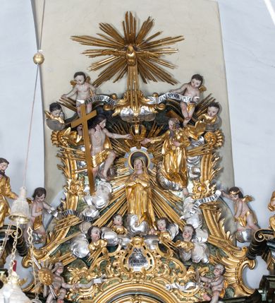 Zdjęcie nr 7: Nastawa ołtarzowa architektoniczna, trójosiowa z bramkami, jednokondygnacyjna ze zwieńczeniem. Ołtarz wysunięty do przodu, drewniany, sarkofagowy, wklęsło-wypukły, zwężający się ku dołowi, na profilowanym cokole, ujęty spływami wolutowymi; dekorowany w narożach palmetami, na froncie rocaille'owy kartusz z malowanymi skrzyżowanymi kluczami w polu. Mensa drewniana z silnie wysuniętą, profilowaną krawędzią, z portatylem z piaskowca. 

Tabernakulum w formie prostopadłościennej skrzynki o wypukłej ściance frontowej, ujęte z przodu ukośnie dostawionymi pilastrami na cokołach z trzonami w formie wolut, dźwigającymi niepełne belkowanie, opasujące je z trzech stron, nad ścianką frontową przyjmujące falistą formę zwieńczoną rocaille'm. Drzwiczki przyjmują kształt stojącego prostokąta zamkniętego łukiem półkolistym nadwieszonym, ujęte profilowaną ramą; w polu płaskorzeźbione przedstawienie kielicha z hostią w glorii na fakturowanym tle. Na belkowaniu, na osi podpór ustawiona jest para rocaille'owych lichtarzy. Tron wystawienia architektoniczny, trójosiowy; oś środkowa ponad tabernakulum w postaci ażurowej niszy z cokołem na pasyjkę, tylna ścianka utworzona z rocaille'u z kłosami zbóż; flankowana pilastrami zwieńczonymi falistym gzymsem, dźwigającymi ażurową, zamkniętą koronę. Podpory przechodzą w spływy wolutowe, ujmujące tabernakulum, na których końcach siedzi para adorujących puttów. Osie boczne są ujęte po bokach pilastrami dźwigającymi imposty podtrzymywane przez rocaille w partii trzonów oraz płonące wazony; pola wypełnione ażurowym rocaille'm i palmetami przechodzącymi w podwójne lichtarze.

Retabulum na planie półowalu, osie boczne ustawione prostopadle do środkowej. Oś środkowa posadowiona na wysokim, dwustrefowym cokole. W pierwszej strefie cokołu prostokątna płycina z napisem: „Z INICJATYWY / KS. PROBOSZCZA ROMANA GORCZYŃSKIEGO / W LATACH 2001 - 2006 / WYKONANO REMONT KOŚCIOŁA I KONSERWACJĘ / WYPOSAŻENIA”. W drugiej strefie cokołu, pośrodku płycina w formie leżącego prostokąta o fantazyjnie wyciętych bokach z malowanym kartuszem herbowym, dzielonym na cztery pola. W lewym górnym polu kartusza umieszczony jest orzeł, poniżej dwójka dzieci w łódce, a po prawej stronie tarczy, w prawym górnym polu dwójka dzieci w łódce, poniżej orzeł. U spodu napis z chronostychem: „EREXIT, AC EXORNAVIT HONORIBVS SANCTI PETRI, / AC PAVLI APOSTOLI ILLVSTRISSIMVS LIBER BAR I WNBS(?) IOANELLY / A TOLVANA PROPPII X I”. Klejnotem jest hełm z pióropuszem zakończony półpostacią rycerza w zbroi, zaś labry mają formę bujnej wici akantowej.  Ryzality cokołów ozdobione są z trzech stron rocaille'owymi płycinami; skrajne konsole rocaille'm i różanymi gałązkami. Oś główna flankowana parą kolumn ustawioną na tle zwielokrotnionych pilastrów. Podpory dźwigają pełne belkowanie, przerwane nad polem środkowym, wyłamane na ich osi oraz przerwany wolutowy przyczółek. W polu środkowym podwójna, profilowana rama w formie stojącego prostokąta zamkniętego łukiem nadwieszonym z uskokami z obrazem św. Piotra i św. Pawła; flankowana przez figury św. Szymona po lewej stronie i św. Judy Tadeusza po prawej, ustawionymi na rocaille'owych wspornikach. Ramy obrazu, trzony wewnętrznych pilastrów i pola za środkową parą figur dekorowane rocaille'm. 

Zwieńczenie w formie zbliżonej do stojącego prostokąta, ujęte spływami wolutowymi, zamknięte falistym gzymsem przechodzącym w antytetycznie zwrócone woluty. Całość zwieńczona gołębicą Ducha Świętego w glorii promienistej. W polu rzeźbiarska grupa Koronacji Marii w glorii promienistej, pośród obłoków i uskrzydlonych główek anielskich. Dwa flankujące grupę putta  na obłokach trzymają banderole z napisem: „FILIA DEI PATRIS” i „MATER DEI FILII”, a kolejne dwa usadzone na szczycie: „VENI CORONABERIS” oraz „VENI SPONSA MEA”. Poniżej zwieńczenia w ażurowym kartuszu znajduje się napis: „QVA E/ST ISTA / QVAE PROGREDI/TUR QVASI AURORA / CONSURGENS / Cant 6.”. Na przyczółku siedzące figury św. Joachima po lewej stronie i św. Józefa po prawej, na gzymsie flankującym pole środkowe dwa putta trzymające słońce i księżyc, na zewnętrznych osiach dwa adorujące anioły. Spływy zwieńczenia dekorowane strzępiastymi liśćmi palmowymi, muszlą i rocaille’m. 

Osie boczne ustawione są na wysokim cokole, od zewnątrz ujęte pilastrami przechodzącymi w woluty, od wewnątrz sąsiadują z osią środkową. Pośrodku bramki z drzwiczkami zakończonymi gzymsem przyjmującym formę cokołu dla figur. Drzwiczki w formie stojącego prostokątna zamkniętego łukiem segmentowym nadwieszonym; osie na skraju ujęte konsolami stanowiącymi cokoły dla podpór. Ryzalit bramek zdobiony płyciną ze strzępiastym grzebieniem; drzwiczki z płyciną z rocaille'm i kwiatowym zwisem na wstążce; powyższy cokół ujęty liśćmi palmowymi i rocaille'm. Kondygnacja flankowana na skraju kolumną ustawioną na tle pilastru, które podtrzymują wyłamany gzyms zakończony wolutami ujmującymi szczyt o falistym przebiegu, na którym ustawiony jest duży płomienisty wazon. W polach ustawione są figury: po lewej się Jakuba Starszego, a po prawej św. Filipa. Na zwieńczeniach usadzone dwie figury aniołów. 

Struktura w całości marmoryzowana w kolorze zielono-brązowym; ornamentyka, kolumny złocone, detale srebrzone. Wszystkie kolumny w jednej trzeciej wysokości przedzielone rocaille’m, a fryz z elementami dekoracji rokokowej. Tabernakulum i tron wystawienia w całości złocone.

