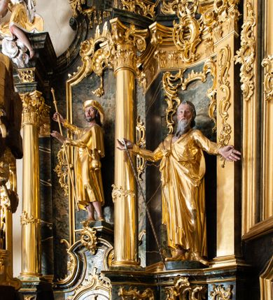 Zdjęcie nr 24: Nastawa ołtarzowa architektoniczna, trójosiowa z bramkami, jednokondygnacyjna ze zwieńczeniem. Ołtarz wysunięty do przodu, drewniany, sarkofagowy, wklęsło-wypukły, zwężający się ku dołowi, na profilowanym cokole, ujęty spływami wolutowymi; dekorowany w narożach palmetami, na froncie rocaille'owy kartusz z malowanymi skrzyżowanymi kluczami w polu. Mensa drewniana z silnie wysuniętą, profilowaną krawędzią, z portatylem z piaskowca. 

Tabernakulum w formie prostopadłościennej skrzynki o wypukłej ściance frontowej, ujęte z przodu ukośnie dostawionymi pilastrami na cokołach z trzonami w formie wolut, dźwigającymi niepełne belkowanie, opasujące je z trzech stron, nad ścianką frontową przyjmujące falistą formę zwieńczoną rocaille'm. Drzwiczki przyjmują kształt stojącego prostokąta zamkniętego łukiem półkolistym nadwieszonym, ujęte profilowaną ramą; w polu płaskorzeźbione przedstawienie kielicha z hostią w glorii na fakturowanym tle. Na belkowaniu, na osi podpór ustawiona jest para rocaille'owych lichtarzy. Tron wystawienia architektoniczny, trójosiowy; oś środkowa ponad tabernakulum w postaci ażurowej niszy z cokołem na pasyjkę, tylna ścianka utworzona z rocaille'u z kłosami zbóż; flankowana pilastrami zwieńczonymi falistym gzymsem, dźwigającymi ażurową, zamkniętą koronę. Podpory przechodzą w spływy wolutowe, ujmujące tabernakulum, na których końcach siedzi para adorujących puttów. Osie boczne są ujęte po bokach pilastrami dźwigającymi imposty podtrzymywane przez rocaille w partii trzonów oraz płonące wazony; pola wypełnione ażurowym rocaille'm i palmetami przechodzącymi w podwójne lichtarze.

Retabulum na planie półowalu, osie boczne ustawione prostopadle do środkowej. Oś środkowa posadowiona na wysokim, dwustrefowym cokole. W pierwszej strefie cokołu prostokątna płycina z napisem: „Z INICJATYWY / KS. PROBOSZCZA ROMANA GORCZYŃSKIEGO / W LATACH 2001 - 2006 / WYKONANO REMONT KOŚCIOŁA I KONSERWACJĘ / WYPOSAŻENIA”. W drugiej strefie cokołu, pośrodku płycina w formie leżącego prostokąta o fantazyjnie wyciętych bokach z malowanym kartuszem herbowym, dzielonym na cztery pola. W lewym górnym polu kartusza umieszczony jest orzeł, poniżej dwójka dzieci w łódce, a po prawej stronie tarczy, w prawym górnym polu dwójka dzieci w łódce, poniżej orzeł. U spodu napis z chronostychem: „EREXIT, AC EXORNAVIT HONORIBVS SANCTI PETRI, / AC PAVLI APOSTOLI ILLVSTRISSIMVS LIBER BAR I WNBS(?) IOANELLY / A TOLVANA PROPPII X I”. Klejnotem jest hełm z pióropuszem zakończony półpostacią rycerza w zbroi, zaś labry mają formę bujnej wici akantowej.  Ryzality cokołów ozdobione są z trzech stron rocaille'owymi płycinami; skrajne konsole rocaille'm i różanymi gałązkami. Oś główna flankowana parą kolumn ustawioną na tle zwielokrotnionych pilastrów. Podpory dźwigają pełne belkowanie, przerwane nad polem środkowym, wyłamane na ich osi oraz przerwany wolutowy przyczółek. W polu środkowym podwójna, profilowana rama w formie stojącego prostokąta zamkniętego łukiem nadwieszonym z uskokami z obrazem św. Piotra i św. Pawła; flankowana przez figury św. Szymona po lewej stronie i św. Judy Tadeusza po prawej, ustawionymi na rocaille'owych wspornikach. Ramy obrazu, trzony wewnętrznych pilastrów i pola za środkową parą figur dekorowane rocaille'm. 

Zwieńczenie w formie zbliżonej do stojącego prostokąta, ujęte spływami wolutowymi, zamknięte falistym gzymsem przechodzącym w antytetycznie zwrócone woluty. Całość zwieńczona gołębicą Ducha Świętego w glorii promienistej. W polu rzeźbiarska grupa Koronacji Marii w glorii promienistej, pośród obłoków i uskrzydlonych główek anielskich. Dwa flankujące grupę putta  na obłokach trzymają banderole z napisem: „FILIA DEI PATRIS” i „MATER DEI FILII”, a kolejne dwa usadzone na szczycie: „VENI CORONABERIS” oraz „VENI SPONSA MEA”. Poniżej zwieńczenia w ażurowym kartuszu znajduje się napis: „QVA E/ST ISTA / QVAE PROGREDI/TUR QVASI AURORA / CONSURGENS / Cant 6.”. Na przyczółku siedzące figury św. Joachima po lewej stronie i św. Józefa po prawej, na gzymsie flankującym pole środkowe dwa putta trzymające słońce i księżyc, na zewnętrznych osiach dwa adorujące anioły. Spływy zwieńczenia dekorowane strzępiastymi liśćmi palmowymi, muszlą i rocaille’m. 

Osie boczne ustawione są na wysokim cokole, od zewnątrz ujęte pilastrami przechodzącymi w woluty, od wewnątrz sąsiadują z osią środkową. Pośrodku bramki z drzwiczkami zakończonymi gzymsem przyjmującym formę cokołu dla figur. Drzwiczki w formie stojącego prostokątna zamkniętego łukiem segmentowym nadwieszonym; osie na skraju ujęte konsolami stanowiącymi cokoły dla podpór. Ryzalit bramek zdobiony płyciną ze strzępiastym grzebieniem; drzwiczki z płyciną z rocaille'm i kwiatowym zwisem na wstążce; powyższy cokół ujęty liśćmi palmowymi i rocaille'm. Kondygnacja flankowana na skraju kolumną ustawioną na tle pilastru, które podtrzymują wyłamany gzyms zakończony wolutami ujmującymi szczyt o falistym przebiegu, na którym ustawiony jest duży płomienisty wazon. W polach ustawione są figury: po lewej się Jakuba Starszego, a po prawej św. Filipa. Na zwieńczeniach usadzone dwie figury aniołów. 

Struktura w całości marmoryzowana w kolorze zielono-brązowym; ornamentyka, kolumny złocone, detale srebrzone. Wszystkie kolumny w jednej trzeciej wysokości przedzielone rocaille’m, a fryz z elementami dekoracji rokokowej. Tabernakulum i tron wystawienia w całości złocone.

