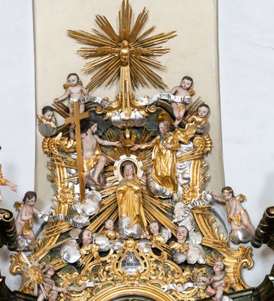 Zdjęcie nr 8: Nastawa ołtarzowa architektoniczna, trójosiowa z bramkami, jednokondygnacyjna ze zwieńczeniem. Ołtarz wysunięty do przodu, drewniany, sarkofagowy, wklęsło-wypukły, zwężający się ku dołowi, na profilowanym cokole, ujęty spływami wolutowymi; dekorowany w narożach palmetami, na froncie rocaille'owy kartusz z malowanymi skrzyżowanymi kluczami w polu. Mensa drewniana z silnie wysuniętą, profilowaną krawędzią, z portatylem z piaskowca. 

Tabernakulum w formie prostopadłościennej skrzynki o wypukłej ściance frontowej, ujęte z przodu ukośnie dostawionymi pilastrami na cokołach z trzonami w formie wolut, dźwigającymi niepełne belkowanie, opasujące je z trzech stron, nad ścianką frontową przyjmujące falistą formę zwieńczoną rocaille'm. Drzwiczki przyjmują kształt stojącego prostokąta zamkniętego łukiem półkolistym nadwieszonym, ujęte profilowaną ramą; w polu płaskorzeźbione przedstawienie kielicha z hostią w glorii na fakturowanym tle. Na belkowaniu, na osi podpór ustawiona jest para rocaille'owych lichtarzy. Tron wystawienia architektoniczny, trójosiowy; oś środkowa ponad tabernakulum w postaci ażurowej niszy z cokołem na pasyjkę, tylna ścianka utworzona z rocaille'u z kłosami zbóż; flankowana pilastrami zwieńczonymi falistym gzymsem, dźwigającymi ażurową, zamkniętą koronę. Podpory przechodzą w spływy wolutowe, ujmujące tabernakulum, na których końcach siedzi para adorujących puttów. Osie boczne są ujęte po bokach pilastrami dźwigającymi imposty podtrzymywane przez rocaille w partii trzonów oraz płonące wazony; pola wypełnione ażurowym rocaille'm i palmetami przechodzącymi w podwójne lichtarze.

Retabulum na planie półowalu, osie boczne ustawione prostopadle do środkowej. Oś środkowa posadowiona na wysokim, dwustrefowym cokole. W pierwszej strefie cokołu prostokątna płycina z napisem: „Z INICJATYWY / KS. PROBOSZCZA ROMANA GORCZYŃSKIEGO / W LATACH 2001 - 2006 / WYKONANO REMONT KOŚCIOŁA I KONSERWACJĘ / WYPOSAŻENIA”. W drugiej strefie cokołu, pośrodku płycina w formie leżącego prostokąta o fantazyjnie wyciętych bokach z malowanym kartuszem herbowym, dzielonym na cztery pola. W lewym górnym polu kartusza umieszczony jest orzeł, poniżej dwójka dzieci w łódce, a po prawej stronie tarczy, w prawym górnym polu dwójka dzieci w łódce, poniżej orzeł. U spodu napis z chronostychem: „EREXIT, AC EXORNAVIT HONORIBVS SANCTI PETRI, / AC PAVLI APOSTOLI ILLVSTRISSIMVS LIBER BAR I WNBS(?) IOANELLY / A TOLVANA PROPPII X I”. Klejnotem jest hełm z pióropuszem zakończony półpostacią rycerza w zbroi, zaś labry mają formę bujnej wici akantowej.  Ryzality cokołów ozdobione są z trzech stron rocaille'owymi płycinami; skrajne konsole rocaille'm i różanymi gałązkami. Oś główna flankowana parą kolumn ustawioną na tle zwielokrotnionych pilastrów. Podpory dźwigają pełne belkowanie, przerwane nad polem środkowym, wyłamane na ich osi oraz przerwany wolutowy przyczółek. W polu środkowym podwójna, profilowana rama w formie stojącego prostokąta zamkniętego łukiem nadwieszonym z uskokami z obrazem św. Piotra i św. Pawła; flankowana przez figury św. Szymona po lewej stronie i św. Judy Tadeusza po prawej, ustawionymi na rocaille'owych wspornikach. Ramy obrazu, trzony wewnętrznych pilastrów i pola za środkową parą figur dekorowane rocaille'm. 

Zwieńczenie w formie zbliżonej do stojącego prostokąta, ujęte spływami wolutowymi, zamknięte falistym gzymsem przechodzącym w antytetycznie zwrócone woluty. Całość zwieńczona gołębicą Ducha Świętego w glorii promienistej. W polu rzeźbiarska grupa Koronacji Marii w glorii promienistej, pośród obłoków i uskrzydlonych główek anielskich. Dwa flankujące grupę putta  na obłokach trzymają banderole z napisem: „FILIA DEI PATRIS” i „MATER DEI FILII”, a kolejne dwa usadzone na szczycie: „VENI CORONABERIS” oraz „VENI SPONSA MEA”. Poniżej zwieńczenia w ażurowym kartuszu znajduje się napis: „QVA E/ST ISTA / QVAE PROGREDI/TUR QVASI AURORA / CONSURGENS / Cant 6.”. Na przyczółku siedzące figury św. Joachima po lewej stronie i św. Józefa po prawej, na gzymsie flankującym pole środkowe dwa putta trzymające słońce i księżyc, na zewnętrznych osiach dwa adorujące anioły. Spływy zwieńczenia dekorowane strzępiastymi liśćmi palmowymi, muszlą i rocaille’m. 

Osie boczne ustawione są na wysokim cokole, od zewnątrz ujęte pilastrami przechodzącymi w woluty, od wewnątrz sąsiadują z osią środkową. Pośrodku bramki z drzwiczkami zakończonymi gzymsem przyjmującym formę cokołu dla figur. Drzwiczki w formie stojącego prostokątna zamkniętego łukiem segmentowym nadwieszonym; osie na skraju ujęte konsolami stanowiącymi cokoły dla podpór. Ryzalit bramek zdobiony płyciną ze strzępiastym grzebieniem; drzwiczki z płyciną z rocaille'm i kwiatowym zwisem na wstążce; powyższy cokół ujęty liśćmi palmowymi i rocaille'm. Kondygnacja flankowana na skraju kolumną ustawioną na tle pilastru, które podtrzymują wyłamany gzyms zakończony wolutami ujmującymi szczyt o falistym przebiegu, na którym ustawiony jest duży płomienisty wazon. W polach ustawione są figury: po lewej się Jakuba Starszego, a po prawej św. Filipa. Na zwieńczeniach usadzone dwie figury aniołów. 

Struktura w całości marmoryzowana w kolorze zielono-brązowym; ornamentyka, kolumny złocone, detale srebrzone. Wszystkie kolumny w jednej trzeciej wysokości przedzielone rocaille’m, a fryz z elementami dekoracji rokokowej. Tabernakulum i tron wystawienia w całości złocone.

