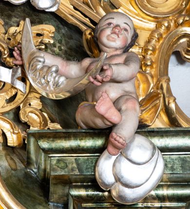 Zdjęcie nr 15: Nastawa ołtarzowa architektoniczna, trójosiowa z bramkami, jednokondygnacyjna ze zwieńczeniem. Ołtarz wysunięty do przodu, drewniany, sarkofagowy, wklęsło-wypukły, zwężający się ku dołowi, na profilowanym cokole, ujęty spływami wolutowymi; dekorowany w narożach palmetami, na froncie rocaille&#039;owy kartusz z malowanymi skrzyżowanymi kluczami w polu. Mensa drewniana z silnie wysuniętą, profilowaną krawędzią, z portatylem z piaskowca. 

Tabernakulum w formie prostopadłościennej skrzynki o wypukłej ściance frontowej, ujęte z przodu ukośnie dostawionymi pilastrami na cokołach z trzonami w formie wolut, dźwigającymi niepełne belkowanie, opasujące je z trzech stron, nad ścianką frontową przyjmujące falistą formę zwieńczoną rocaille&#039;m. Drzwiczki przyjmują kształt stojącego prostokąta zamkniętego łukiem półkolistym nadwieszonym, ujęte profilowaną ramą; w polu płaskorzeźbione przedstawienie kielicha z hostią w glorii na fakturowanym tle. Na belkowaniu, na osi podpór ustawiona jest para rocaille&#039;owych lichtarzy. Tron wystawienia architektoniczny, trójosiowy; oś środkowa ponad tabernakulum w postaci ażurowej niszy z cokołem na pasyjkę, tylna ścianka utworzona z rocaille&#039;u z kłosami zbóż; flankowana pilastrami zwieńczonymi falistym gzymsem, dźwigającymi ażurową, zamkniętą koronę. Podpory przechodzą w spływy wolutowe, ujmujące tabernakulum, na których końcach siedzi para adorujących puttów. Osie boczne są ujęte po bokach pilastrami dźwigającymi imposty podtrzymywane przez rocaille w partii trzonów oraz płonące wazony; pola wypełnione ażurowym rocaille&#039;m i palmetami przechodzącymi w podwójne lichtarze.

Retabulum na planie półowalu, osie boczne ustawione prostopadle do środkowej. Oś środkowa posadowiona na wysokim, dwustrefowym cokole. W pierwszej strefie cokołu prostokątna płycina z napisem: „Z INICJATYWY / KS. PROBOSZCZA ROMANA GORCZYŃSKIEGO / W LATACH 2001 - 2006 / WYKONANO REMONT KOŚCIOŁA I KONSERWACJĘ / WYPOSAŻENIA”. W drugiej strefie cokołu, pośrodku płycina w formie leżącego prostokąta o fantazyjnie wyciętych bokach z malowanym kartuszem herbowym, dzielonym na cztery pola. W lewym górnym polu kartusza umieszczony jest orzeł, poniżej dwójka dzieci w łódce, a po prawej stronie tarczy, w prawym górnym polu dwójka dzieci w łódce, poniżej orzeł. U spodu napis z chronostychem: „EREXIT, AC EXORNAVIT HONORIBVS SANCTI PETRI, / AC PAVLI APOSTOLI ILLVSTRISSIMVS LIBER BAR I WNBS(?) IOANELLY / A TOLVANA PROPPII X I”. Klejnotem jest hełm z pióropuszem zakończony półpostacią rycerza w zbroi, zaś labry mają formę bujnej wici akantowej.  Ryzality cokołów ozdobione są z trzech stron rocaille&#039;owymi płycinami; skrajne konsole rocaille&#039;m i różanymi gałązkami. Oś główna flankowana parą kolumn ustawioną na tle zwielokrotnionych pilastrów. Podpory dźwigają pełne belkowanie, przerwane nad polem środkowym, wyłamane na ich osi oraz przerwany wolutowy przyczółek. W polu środkowym podwójna, profilowana rama w formie stojącego prostokąta zamkniętego łukiem nadwieszonym z uskokami z obrazem św. Piotra i św. Pawła; flankowana przez figury św. Szymona po lewej stronie i św. Judy Tadeusza po prawej, ustawionymi na rocaille&#039;owych wspornikach. Ramy obrazu, trzony wewnętrznych pilastrów i pola za środkową parą figur dekorowane rocaille&#039;m. 

Zwieńczenie w formie zbliżonej do stojącego prostokąta, ujęte spływami wolutowymi, zamknięte falistym gzymsem przechodzącym w antytetycznie zwrócone woluty. Całość zwieńczona gołębicą Ducha Świętego w glorii promienistej. W polu rzeźbiarska grupa Koronacji Marii w glorii promienistej, pośród obłoków i uskrzydlonych główek anielskich. Dwa flankujące grupę putta  na obłokach trzymają banderole z napisem: „FILIA DEI PATRIS” i „MATER DEI FILII”, a kolejne dwa usadzone na szczycie: „VENI CORONABERIS” oraz „VENI SPONSA MEA”. Poniżej zwieńczenia w ażurowym kartuszu znajduje się napis: „QVA E/ST ISTA / QVAE PROGREDI/TUR QVASI AURORA / CONSURGENS / Cant 6.”. Na przyczółku siedzące figury św. Joachima po lewej stronie i św. Józefa po prawej, na gzymsie flankującym pole środkowe dwa putta trzymające słońce i księżyc, na zewnętrznych osiach dwa adorujące anioły. Spływy zwieńczenia dekorowane strzępiastymi liśćmi palmowymi, muszlą i rocaille’m. 

Osie boczne ustawione są na wysokim cokole, od zewnątrz ujęte pilastrami przechodzącymi w woluty, od wewnątrz sąsiadują z osią środkową. Pośrodku bramki z drzwiczkami zakończonymi gzymsem przyjmującym formę cokołu dla figur. Drzwiczki w formie stojącego prostokątna zamkniętego łukiem segmentowym nadwieszonym; osie na skraju ujęte konsolami stanowiącymi cokoły dla podpór. Ryzalit bramek zdobiony płyciną ze strzępiastym grzebieniem; drzwiczki z płyciną z rocaille&#039;m i kwiatowym zwisem na wstążce; powyższy cokół ujęty liśćmi palmowymi i rocaille&#039;m. Kondygnacja flankowana na skraju kolumną ustawioną na tle pilastru, które podtrzymują wyłamany gzyms zakończony wolutami ujmującymi szczyt o falistym przebiegu, na którym ustawiony jest duży płomienisty wazon. W polach ustawione są figury: po lewej się Jakuba Starszego, a po prawej św. Filipa. Na zwieńczeniach usadzone dwie figury aniołów. 

Struktura w całości marmoryzowana w kolorze zielono-brązowym; ornamentyka, kolumny złocone, detale srebrzone. Wszystkie kolumny w jednej trzeciej wysokości przedzielone rocaille’m, a fryz z elementami dekoracji rokokowej. Tabernakulum i tron wystawienia w całości złocone.

