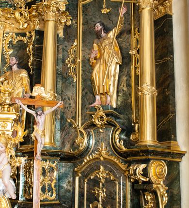 Zdjęcie nr 22: Nastawa ołtarzowa architektoniczna, trójosiowa z bramkami, jednokondygnacyjna ze zwieńczeniem. Ołtarz wysunięty do przodu, drewniany, sarkofagowy, wklęsło-wypukły, zwężający się ku dołowi, na profilowanym cokole, ujęty spływami wolutowymi; dekorowany w narożach palmetami, na froncie rocaille'owy kartusz z malowanymi skrzyżowanymi kluczami w polu. Mensa drewniana z silnie wysuniętą, profilowaną krawędzią, z portatylem z piaskowca. 

Tabernakulum w formie prostopadłościennej skrzynki o wypukłej ściance frontowej, ujęte z przodu ukośnie dostawionymi pilastrami na cokołach z trzonami w formie wolut, dźwigającymi niepełne belkowanie, opasujące je z trzech stron, nad ścianką frontową przyjmujące falistą formę zwieńczoną rocaille'm. Drzwiczki przyjmują kształt stojącego prostokąta zamkniętego łukiem półkolistym nadwieszonym, ujęte profilowaną ramą; w polu płaskorzeźbione przedstawienie kielicha z hostią w glorii na fakturowanym tle. Na belkowaniu, na osi podpór ustawiona jest para rocaille'owych lichtarzy. Tron wystawienia architektoniczny, trójosiowy; oś środkowa ponad tabernakulum w postaci ażurowej niszy z cokołem na pasyjkę, tylna ścianka utworzona z rocaille'u z kłosami zbóż; flankowana pilastrami zwieńczonymi falistym gzymsem, dźwigającymi ażurową, zamkniętą koronę. Podpory przechodzą w spływy wolutowe, ujmujące tabernakulum, na których końcach siedzi para adorujących puttów. Osie boczne są ujęte po bokach pilastrami dźwigającymi imposty podtrzymywane przez rocaille w partii trzonów oraz płonące wazony; pola wypełnione ażurowym rocaille'm i palmetami przechodzącymi w podwójne lichtarze.

Retabulum na planie półowalu, osie boczne ustawione prostopadle do środkowej. Oś środkowa posadowiona na wysokim, dwustrefowym cokole. W pierwszej strefie cokołu prostokątna płycina z napisem: „Z INICJATYWY / KS. PROBOSZCZA ROMANA GORCZYŃSKIEGO / W LATACH 2001 - 2006 / WYKONANO REMONT KOŚCIOŁA I KONSERWACJĘ / WYPOSAŻENIA”. W drugiej strefie cokołu, pośrodku płycina w formie leżącego prostokąta o fantazyjnie wyciętych bokach z malowanym kartuszem herbowym, dzielonym na cztery pola. W lewym górnym polu kartusza umieszczony jest orzeł, poniżej dwójka dzieci w łódce, a po prawej stronie tarczy, w prawym górnym polu dwójka dzieci w łódce, poniżej orzeł. U spodu napis z chronostychem: „EREXIT, AC EXORNAVIT HONORIBVS SANCTI PETRI, / AC PAVLI APOSTOLI ILLVSTRISSIMVS LIBER BAR I WNBS(?) IOANELLY / A TOLVANA PROPPII X I”. Klejnotem jest hełm z pióropuszem zakończony półpostacią rycerza w zbroi, zaś labry mają formę bujnej wici akantowej.  Ryzality cokołów ozdobione są z trzech stron rocaille'owymi płycinami; skrajne konsole rocaille'm i różanymi gałązkami. Oś główna flankowana parą kolumn ustawioną na tle zwielokrotnionych pilastrów. Podpory dźwigają pełne belkowanie, przerwane nad polem środkowym, wyłamane na ich osi oraz przerwany wolutowy przyczółek. W polu środkowym podwójna, profilowana rama w formie stojącego prostokąta zamkniętego łukiem nadwieszonym z uskokami z obrazem św. Piotra i św. Pawła; flankowana przez figury św. Szymona po lewej stronie i św. Judy Tadeusza po prawej, ustawionymi na rocaille'owych wspornikach. Ramy obrazu, trzony wewnętrznych pilastrów i pola za środkową parą figur dekorowane rocaille'm. 

Zwieńczenie w formie zbliżonej do stojącego prostokąta, ujęte spływami wolutowymi, zamknięte falistym gzymsem przechodzącym w antytetycznie zwrócone woluty. Całość zwieńczona gołębicą Ducha Świętego w glorii promienistej. W polu rzeźbiarska grupa Koronacji Marii w glorii promienistej, pośród obłoków i uskrzydlonych główek anielskich. Dwa flankujące grupę putta  na obłokach trzymają banderole z napisem: „FILIA DEI PATRIS” i „MATER DEI FILII”, a kolejne dwa usadzone na szczycie: „VENI CORONABERIS” oraz „VENI SPONSA MEA”. Poniżej zwieńczenia w ażurowym kartuszu znajduje się napis: „QVA E/ST ISTA / QVAE PROGREDI/TUR QVASI AURORA / CONSURGENS / Cant 6.”. Na przyczółku siedzące figury św. Joachima po lewej stronie i św. Józefa po prawej, na gzymsie flankującym pole środkowe dwa putta trzymające słońce i księżyc, na zewnętrznych osiach dwa adorujące anioły. Spływy zwieńczenia dekorowane strzępiastymi liśćmi palmowymi, muszlą i rocaille’m. 

Osie boczne ustawione są na wysokim cokole, od zewnątrz ujęte pilastrami przechodzącymi w woluty, od wewnątrz sąsiadują z osią środkową. Pośrodku bramki z drzwiczkami zakończonymi gzymsem przyjmującym formę cokołu dla figur. Drzwiczki w formie stojącego prostokątna zamkniętego łukiem segmentowym nadwieszonym; osie na skraju ujęte konsolami stanowiącymi cokoły dla podpór. Ryzalit bramek zdobiony płyciną ze strzępiastym grzebieniem; drzwiczki z płyciną z rocaille'm i kwiatowym zwisem na wstążce; powyższy cokół ujęty liśćmi palmowymi i rocaille'm. Kondygnacja flankowana na skraju kolumną ustawioną na tle pilastru, które podtrzymują wyłamany gzyms zakończony wolutami ujmującymi szczyt o falistym przebiegu, na którym ustawiony jest duży płomienisty wazon. W polach ustawione są figury: po lewej się Jakuba Starszego, a po prawej św. Filipa. Na zwieńczeniach usadzone dwie figury aniołów. 

Struktura w całości marmoryzowana w kolorze zielono-brązowym; ornamentyka, kolumny złocone, detale srebrzone. Wszystkie kolumny w jednej trzeciej wysokości przedzielone rocaille’m, a fryz z elementami dekoracji rokokowej. Tabernakulum i tron wystawienia w całości złocone.

