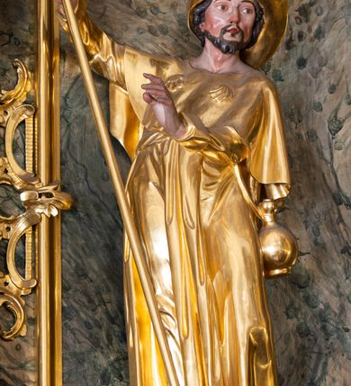 Zdjęcie nr 25: Nastawa ołtarzowa architektoniczna, trójosiowa z bramkami, jednokondygnacyjna ze zwieńczeniem. Ołtarz wysunięty do przodu, drewniany, sarkofagowy, wklęsło-wypukły, zwężający się ku dołowi, na profilowanym cokole, ujęty spływami wolutowymi; dekorowany w narożach palmetami, na froncie rocaille'owy kartusz z malowanymi skrzyżowanymi kluczami w polu. Mensa drewniana z silnie wysuniętą, profilowaną krawędzią, z portatylem z piaskowca. 

Tabernakulum w formie prostopadłościennej skrzynki o wypukłej ściance frontowej, ujęte z przodu ukośnie dostawionymi pilastrami na cokołach z trzonami w formie wolut, dźwigającymi niepełne belkowanie, opasujące je z trzech stron, nad ścianką frontową przyjmujące falistą formę zwieńczoną rocaille'm. Drzwiczki przyjmują kształt stojącego prostokąta zamkniętego łukiem półkolistym nadwieszonym, ujęte profilowaną ramą; w polu płaskorzeźbione przedstawienie kielicha z hostią w glorii na fakturowanym tle. Na belkowaniu, na osi podpór ustawiona jest para rocaille'owych lichtarzy. Tron wystawienia architektoniczny, trójosiowy; oś środkowa ponad tabernakulum w postaci ażurowej niszy z cokołem na pasyjkę, tylna ścianka utworzona z rocaille'u z kłosami zbóż; flankowana pilastrami zwieńczonymi falistym gzymsem, dźwigającymi ażurową, zamkniętą koronę. Podpory przechodzą w spływy wolutowe, ujmujące tabernakulum, na których końcach siedzi para adorujących puttów. Osie boczne są ujęte po bokach pilastrami dźwigającymi imposty podtrzymywane przez rocaille w partii trzonów oraz płonące wazony; pola wypełnione ażurowym rocaille'm i palmetami przechodzącymi w podwójne lichtarze.

Retabulum na planie półowalu, osie boczne ustawione prostopadle do środkowej. Oś środkowa posadowiona na wysokim, dwustrefowym cokole. W pierwszej strefie cokołu prostokątna płycina z napisem: „Z INICJATYWY / KS. PROBOSZCZA ROMANA GORCZYŃSKIEGO / W LATACH 2001 - 2006 / WYKONANO REMONT KOŚCIOŁA I KONSERWACJĘ / WYPOSAŻENIA”. W drugiej strefie cokołu, pośrodku płycina w formie leżącego prostokąta o fantazyjnie wyciętych bokach z malowanym kartuszem herbowym, dzielonym na cztery pola. W lewym górnym polu kartusza umieszczony jest orzeł, poniżej dwójka dzieci w łódce, a po prawej stronie tarczy, w prawym górnym polu dwójka dzieci w łódce, poniżej orzeł. U spodu napis z chronostychem: „EREXIT, AC EXORNAVIT HONORIBVS SANCTI PETRI, / AC PAVLI APOSTOLI ILLVSTRISSIMVS LIBER BAR I WNBS(?) IOANELLY / A TOLVANA PROPPII X I”. Klejnotem jest hełm z pióropuszem zakończony półpostacią rycerza w zbroi, zaś labry mają formę bujnej wici akantowej.  Ryzality cokołów ozdobione są z trzech stron rocaille'owymi płycinami; skrajne konsole rocaille'm i różanymi gałązkami. Oś główna flankowana parą kolumn ustawioną na tle zwielokrotnionych pilastrów. Podpory dźwigają pełne belkowanie, przerwane nad polem środkowym, wyłamane na ich osi oraz przerwany wolutowy przyczółek. W polu środkowym podwójna, profilowana rama w formie stojącego prostokąta zamkniętego łukiem nadwieszonym z uskokami z obrazem św. Piotra i św. Pawła; flankowana przez figury św. Szymona po lewej stronie i św. Judy Tadeusza po prawej, ustawionymi na rocaille'owych wspornikach. Ramy obrazu, trzony wewnętrznych pilastrów i pola za środkową parą figur dekorowane rocaille'm. 

Zwieńczenie w formie zbliżonej do stojącego prostokąta, ujęte spływami wolutowymi, zamknięte falistym gzymsem przechodzącym w antytetycznie zwrócone woluty. Całość zwieńczona gołębicą Ducha Świętego w glorii promienistej. W polu rzeźbiarska grupa Koronacji Marii w glorii promienistej, pośród obłoków i uskrzydlonych główek anielskich. Dwa flankujące grupę putta  na obłokach trzymają banderole z napisem: „FILIA DEI PATRIS” i „MATER DEI FILII”, a kolejne dwa usadzone na szczycie: „VENI CORONABERIS” oraz „VENI SPONSA MEA”. Poniżej zwieńczenia w ażurowym kartuszu znajduje się napis: „QVA E/ST ISTA / QVAE PROGREDI/TUR QVASI AURORA / CONSURGENS / Cant 6.”. Na przyczółku siedzące figury św. Joachima po lewej stronie i św. Józefa po prawej, na gzymsie flankującym pole środkowe dwa putta trzymające słońce i księżyc, na zewnętrznych osiach dwa adorujące anioły. Spływy zwieńczenia dekorowane strzępiastymi liśćmi palmowymi, muszlą i rocaille’m. 

Osie boczne ustawione są na wysokim cokole, od zewnątrz ujęte pilastrami przechodzącymi w woluty, od wewnątrz sąsiadują z osią środkową. Pośrodku bramki z drzwiczkami zakończonymi gzymsem przyjmującym formę cokołu dla figur. Drzwiczki w formie stojącego prostokątna zamkniętego łukiem segmentowym nadwieszonym; osie na skraju ujęte konsolami stanowiącymi cokoły dla podpór. Ryzalit bramek zdobiony płyciną ze strzępiastym grzebieniem; drzwiczki z płyciną z rocaille'm i kwiatowym zwisem na wstążce; powyższy cokół ujęty liśćmi palmowymi i rocaille'm. Kondygnacja flankowana na skraju kolumną ustawioną na tle pilastru, które podtrzymują wyłamany gzyms zakończony wolutami ujmującymi szczyt o falistym przebiegu, na którym ustawiony jest duży płomienisty wazon. W polach ustawione są figury: po lewej się Jakuba Starszego, a po prawej św. Filipa. Na zwieńczeniach usadzone dwie figury aniołów. 

Struktura w całości marmoryzowana w kolorze zielono-brązowym; ornamentyka, kolumny złocone, detale srebrzone. Wszystkie kolumny w jednej trzeciej wysokości przedzielone rocaille’m, a fryz z elementami dekoracji rokokowej. Tabernakulum i tron wystawienia w całości złocone.

