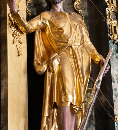 Zdjęcie nr 29: Nastawa ołtarzowa architektoniczna, trójosiowa z bramkami, jednokondygnacyjna ze zwieńczeniem. Ołtarz wysunięty do przodu, drewniany, sarkofagowy, wklęsło-wypukły, zwężający się ku dołowi, na profilowanym cokole, ujęty spływami wolutowymi; dekorowany w narożach palmetami, na froncie rocaille'owy kartusz z malowanymi skrzyżowanymi kluczami w polu. Mensa drewniana z silnie wysuniętą, profilowaną krawędzią, z portatylem z piaskowca. 

Tabernakulum w formie prostopadłościennej skrzynki o wypukłej ściance frontowej, ujęte z przodu ukośnie dostawionymi pilastrami na cokołach z trzonami w formie wolut, dźwigającymi niepełne belkowanie, opasujące je z trzech stron, nad ścianką frontową przyjmujące falistą formę zwieńczoną rocaille'm. Drzwiczki przyjmują kształt stojącego prostokąta zamkniętego łukiem półkolistym nadwieszonym, ujęte profilowaną ramą; w polu płaskorzeźbione przedstawienie kielicha z hostią w glorii na fakturowanym tle. Na belkowaniu, na osi podpór ustawiona jest para rocaille'owych lichtarzy. Tron wystawienia architektoniczny, trójosiowy; oś środkowa ponad tabernakulum w postaci ażurowej niszy z cokołem na pasyjkę, tylna ścianka utworzona z rocaille'u z kłosami zbóż; flankowana pilastrami zwieńczonymi falistym gzymsem, dźwigającymi ażurową, zamkniętą koronę. Podpory przechodzą w spływy wolutowe, ujmujące tabernakulum, na których końcach siedzi para adorujących puttów. Osie boczne są ujęte po bokach pilastrami dźwigającymi imposty podtrzymywane przez rocaille w partii trzonów oraz płonące wazony; pola wypełnione ażurowym rocaille'm i palmetami przechodzącymi w podwójne lichtarze.

Retabulum na planie półowalu, osie boczne ustawione prostopadle do środkowej. Oś środkowa posadowiona na wysokim, dwustrefowym cokole. W pierwszej strefie cokołu prostokątna płycina z napisem: „Z INICJATYWY / KS. PROBOSZCZA ROMANA GORCZYŃSKIEGO / W LATACH 2001 - 2006 / WYKONANO REMONT KOŚCIOŁA I KONSERWACJĘ / WYPOSAŻENIA”. W drugiej strefie cokołu, pośrodku płycina w formie leżącego prostokąta o fantazyjnie wyciętych bokach z malowanym kartuszem herbowym, dzielonym na cztery pola. W lewym górnym polu kartusza umieszczony jest orzeł, poniżej dwójka dzieci w łódce, a po prawej stronie tarczy, w prawym górnym polu dwójka dzieci w łódce, poniżej orzeł. U spodu napis z chronostychem: „EREXIT, AC EXORNAVIT HONORIBVS SANCTI PETRI, / AC PAVLI APOSTOLI ILLVSTRISSIMVS LIBER BAR I WNBS(?) IOANELLY / A TOLVANA PROPPII X I”. Klejnotem jest hełm z pióropuszem zakończony półpostacią rycerza w zbroi, zaś labry mają formę bujnej wici akantowej.  Ryzality cokołów ozdobione są z trzech stron rocaille'owymi płycinami; skrajne konsole rocaille'm i różanymi gałązkami. Oś główna flankowana parą kolumn ustawioną na tle zwielokrotnionych pilastrów. Podpory dźwigają pełne belkowanie, przerwane nad polem środkowym, wyłamane na ich osi oraz przerwany wolutowy przyczółek. W polu środkowym podwójna, profilowana rama w formie stojącego prostokąta zamkniętego łukiem nadwieszonym z uskokami z obrazem św. Piotra i św. Pawła; flankowana przez figury św. Szymona po lewej stronie i św. Judy Tadeusza po prawej, ustawionymi na rocaille'owych wspornikach. Ramy obrazu, trzony wewnętrznych pilastrów i pola za środkową parą figur dekorowane rocaille'm. 

Zwieńczenie w formie zbliżonej do stojącego prostokąta, ujęte spływami wolutowymi, zamknięte falistym gzymsem przechodzącym w antytetycznie zwrócone woluty. Całość zwieńczona gołębicą Ducha Świętego w glorii promienistej. W polu rzeźbiarska grupa Koronacji Marii w glorii promienistej, pośród obłoków i uskrzydlonych główek anielskich. Dwa flankujące grupę putta  na obłokach trzymają banderole z napisem: „FILIA DEI PATRIS” i „MATER DEI FILII”, a kolejne dwa usadzone na szczycie: „VENI CORONABERIS” oraz „VENI SPONSA MEA”. Poniżej zwieńczenia w ażurowym kartuszu znajduje się napis: „QVA E/ST ISTA / QVAE PROGREDI/TUR QVASI AURORA / CONSURGENS / Cant 6.”. Na przyczółku siedzące figury św. Joachima po lewej stronie i św. Józefa po prawej, na gzymsie flankującym pole środkowe dwa putta trzymające słońce i księżyc, na zewnętrznych osiach dwa adorujące anioły. Spływy zwieńczenia dekorowane strzępiastymi liśćmi palmowymi, muszlą i rocaille’m. 

Osie boczne ustawione są na wysokim cokole, od zewnątrz ujęte pilastrami przechodzącymi w woluty, od wewnątrz sąsiadują z osią środkową. Pośrodku bramki z drzwiczkami zakończonymi gzymsem przyjmującym formę cokołu dla figur. Drzwiczki w formie stojącego prostokątna zamkniętego łukiem segmentowym nadwieszonym; osie na skraju ujęte konsolami stanowiącymi cokoły dla podpór. Ryzalit bramek zdobiony płyciną ze strzępiastym grzebieniem; drzwiczki z płyciną z rocaille'm i kwiatowym zwisem na wstążce; powyższy cokół ujęty liśćmi palmowymi i rocaille'm. Kondygnacja flankowana na skraju kolumną ustawioną na tle pilastru, które podtrzymują wyłamany gzyms zakończony wolutami ujmującymi szczyt o falistym przebiegu, na którym ustawiony jest duży płomienisty wazon. W polach ustawione są figury: po lewej się Jakuba Starszego, a po prawej św. Filipa. Na zwieńczeniach usadzone dwie figury aniołów. 

Struktura w całości marmoryzowana w kolorze zielono-brązowym; ornamentyka, kolumny złocone, detale srebrzone. Wszystkie kolumny w jednej trzeciej wysokości przedzielone rocaille’m, a fryz z elementami dekoracji rokokowej. Tabernakulum i tron wystawienia w całości złocone.

