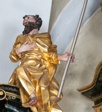 Zdjęcie nr 20: Nastawa ołtarzowa architektoniczna, trójosiowa z bramkami, jednokondygnacyjna ze zwieńczeniem. Ołtarz wysunięty do przodu, drewniany, sarkofagowy, wklęsło-wypukły, zwężający się ku dołowi, na profilowanym cokole, ujęty spływami wolutowymi; dekorowany w narożach palmetami, na froncie rocaille&#039;owy kartusz z malowanymi skrzyżowanymi kluczami w polu. Mensa drewniana z silnie wysuniętą, profilowaną krawędzią, z portatylem z piaskowca. 

Tabernakulum w formie prostopadłościennej skrzynki o wypukłej ściance frontowej, ujęte z przodu ukośnie dostawionymi pilastrami na cokołach z trzonami w formie wolut, dźwigającymi niepełne belkowanie, opasujące je z trzech stron, nad ścianką frontową przyjmujące falistą formę zwieńczoną rocaille&#039;m. Drzwiczki przyjmują kształt stojącego prostokąta zamkniętego łukiem półkolistym nadwieszonym, ujęte profilowaną ramą; w polu płaskorzeźbione przedstawienie kielicha z hostią w glorii na fakturowanym tle. Na belkowaniu, na osi podpór ustawiona jest para rocaille&#039;owych lichtarzy. Tron wystawienia architektoniczny, trójosiowy; oś środkowa ponad tabernakulum w postaci ażurowej niszy z cokołem na pasyjkę, tylna ścianka utworzona z rocaille&#039;u z kłosami zbóż; flankowana pilastrami zwieńczonymi falistym gzymsem, dźwigającymi ażurową, zamkniętą koronę. Podpory przechodzą w spływy wolutowe, ujmujące tabernakulum, na których końcach siedzi para adorujących puttów. Osie boczne są ujęte po bokach pilastrami dźwigającymi imposty podtrzymywane przez rocaille w partii trzonów oraz płonące wazony; pola wypełnione ażurowym rocaille&#039;m i palmetami przechodzącymi w podwójne lichtarze.

Retabulum na planie półowalu, osie boczne ustawione prostopadle do środkowej. Oś środkowa posadowiona na wysokim, dwustrefowym cokole. W pierwszej strefie cokołu prostokątna płycina z napisem: „Z INICJATYWY / KS. PROBOSZCZA ROMANA GORCZYŃSKIEGO / W LATACH 2001 - 2006 / WYKONANO REMONT KOŚCIOŁA I KONSERWACJĘ / WYPOSAŻENIA”. W drugiej strefie cokołu, pośrodku płycina w formie leżącego prostokąta o fantazyjnie wyciętych bokach z malowanym kartuszem herbowym, dzielonym na cztery pola. W lewym górnym polu kartusza umieszczony jest orzeł, poniżej dwójka dzieci w łódce, a po prawej stronie tarczy, w prawym górnym polu dwójka dzieci w łódce, poniżej orzeł. U spodu napis z chronostychem: „EREXIT, AC EXORNAVIT HONORIBVS SANCTI PETRI, / AC PAVLI APOSTOLI ILLVSTRISSIMVS LIBER BAR I WNBS(?) IOANELLY / A TOLVANA PROPPII X I”. Klejnotem jest hełm z pióropuszem zakończony półpostacią rycerza w zbroi, zaś labry mają formę bujnej wici akantowej.  Ryzality cokołów ozdobione są z trzech stron rocaille&#039;owymi płycinami; skrajne konsole rocaille&#039;m i różanymi gałązkami. Oś główna flankowana parą kolumn ustawioną na tle zwielokrotnionych pilastrów. Podpory dźwigają pełne belkowanie, przerwane nad polem środkowym, wyłamane na ich osi oraz przerwany wolutowy przyczółek. W polu środkowym podwójna, profilowana rama w formie stojącego prostokąta zamkniętego łukiem nadwieszonym z uskokami z obrazem św. Piotra i św. Pawła; flankowana przez figury św. Szymona po lewej stronie i św. Judy Tadeusza po prawej, ustawionymi na rocaille&#039;owych wspornikach. Ramy obrazu, trzony wewnętrznych pilastrów i pola za środkową parą figur dekorowane rocaille&#039;m. 

Zwieńczenie w formie zbliżonej do stojącego prostokąta, ujęte spływami wolutowymi, zamknięte falistym gzymsem przechodzącym w antytetycznie zwrócone woluty. Całość zwieńczona gołębicą Ducha Świętego w glorii promienistej. W polu rzeźbiarska grupa Koronacji Marii w glorii promienistej, pośród obłoków i uskrzydlonych główek anielskich. Dwa flankujące grupę putta  na obłokach trzymają banderole z napisem: „FILIA DEI PATRIS” i „MATER DEI FILII”, a kolejne dwa usadzone na szczycie: „VENI CORONABERIS” oraz „VENI SPONSA MEA”. Poniżej zwieńczenia w ażurowym kartuszu znajduje się napis: „QVA E/ST ISTA / QVAE PROGREDI/TUR QVASI AURORA / CONSURGENS / Cant 6.”. Na przyczółku siedzące figury św. Joachima po lewej stronie i św. Józefa po prawej, na gzymsie flankującym pole środkowe dwa putta trzymające słońce i księżyc, na zewnętrznych osiach dwa adorujące anioły. Spływy zwieńczenia dekorowane strzępiastymi liśćmi palmowymi, muszlą i rocaille’m. 

Osie boczne ustawione są na wysokim cokole, od zewnątrz ujęte pilastrami przechodzącymi w woluty, od wewnątrz sąsiadują z osią środkową. Pośrodku bramki z drzwiczkami zakończonymi gzymsem przyjmującym formę cokołu dla figur. Drzwiczki w formie stojącego prostokątna zamkniętego łukiem segmentowym nadwieszonym; osie na skraju ujęte konsolami stanowiącymi cokoły dla podpór. Ryzalit bramek zdobiony płyciną ze strzępiastym grzebieniem; drzwiczki z płyciną z rocaille&#039;m i kwiatowym zwisem na wstążce; powyższy cokół ujęty liśćmi palmowymi i rocaille&#039;m. Kondygnacja flankowana na skraju kolumną ustawioną na tle pilastru, które podtrzymują wyłamany gzyms zakończony wolutami ujmującymi szczyt o falistym przebiegu, na którym ustawiony jest duży płomienisty wazon. W polach ustawione są figury: po lewej się Jakuba Starszego, a po prawej św. Filipa. Na zwieńczeniach usadzone dwie figury aniołów. 

Struktura w całości marmoryzowana w kolorze zielono-brązowym; ornamentyka, kolumny złocone, detale srebrzone. Wszystkie kolumny w jednej trzeciej wysokości przedzielone rocaille’m, a fryz z elementami dekoracji rokokowej. Tabernakulum i tron wystawienia w całości złocone.

