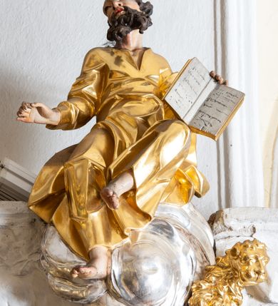 Zdjęcie nr 35: Nastawa ołtarzowa architektoniczna, trójosiowa z bramkami, jednokondygnacyjna ze zwieńczeniem. Ołtarz wysunięty do przodu, drewniany, sarkofagowy, wklęsło-wypukły, zwężający się ku dołowi, na profilowanym cokole, ujęty spływami wolutowymi; dekorowany w narożach palmetami, na froncie rocaille&#039;owy kartusz z malowanymi skrzyżowanymi kluczami w polu. Mensa drewniana z silnie wysuniętą, profilowaną krawędzią, z portatylem z piaskowca. 

Tabernakulum w formie prostopadłościennej skrzynki o wypukłej ściance frontowej, ujęte z przodu ukośnie dostawionymi pilastrami na cokołach z trzonami w formie wolut, dźwigającymi niepełne belkowanie, opasujące je z trzech stron, nad ścianką frontową przyjmujące falistą formę zwieńczoną rocaille&#039;m. Drzwiczki przyjmują kształt stojącego prostokąta zamkniętego łukiem półkolistym nadwieszonym, ujęte profilowaną ramą; w polu płaskorzeźbione przedstawienie kielicha z hostią w glorii na fakturowanym tle. Na belkowaniu, na osi podpór ustawiona jest para rocaille&#039;owych lichtarzy. Tron wystawienia architektoniczny, trójosiowy; oś środkowa ponad tabernakulum w postaci ażurowej niszy z cokołem na pasyjkę, tylna ścianka utworzona z rocaille&#039;u z kłosami zbóż; flankowana pilastrami zwieńczonymi falistym gzymsem, dźwigającymi ażurową, zamkniętą koronę. Podpory przechodzą w spływy wolutowe, ujmujące tabernakulum, na których końcach siedzi para adorujących puttów. Osie boczne są ujęte po bokach pilastrami dźwigającymi imposty podtrzymywane przez rocaille w partii trzonów oraz płonące wazony; pola wypełnione ażurowym rocaille&#039;m i palmetami przechodzącymi w podwójne lichtarze.

Retabulum na planie półowalu, osie boczne ustawione prostopadle do środkowej. Oś środkowa posadowiona na wysokim, dwustrefowym cokole. W pierwszej strefie cokołu prostokątna płycina z napisem: „Z INICJATYWY / KS. PROBOSZCZA ROMANA GORCZYŃSKIEGO / W LATACH 2001 - 2006 / WYKONANO REMONT KOŚCIOŁA I KONSERWACJĘ / WYPOSAŻENIA”. W drugiej strefie cokołu, pośrodku płycina w formie leżącego prostokąta o fantazyjnie wyciętych bokach z malowanym kartuszem herbowym, dzielonym na cztery pola. W lewym górnym polu kartusza umieszczony jest orzeł, poniżej dwójka dzieci w łódce, a po prawej stronie tarczy, w prawym górnym polu dwójka dzieci w łódce, poniżej orzeł. U spodu napis z chronostychem: „EREXIT, AC EXORNAVIT HONORIBVS SANCTI PETRI, / AC PAVLI APOSTOLI ILLVSTRISSIMVS LIBER BAR I WNBS(?) IOANELLY / A TOLVANA PROPPII X I”. Klejnotem jest hełm z pióropuszem zakończony półpostacią rycerza w zbroi, zaś labry mają formę bujnej wici akantowej.  Ryzality cokołów ozdobione są z trzech stron rocaille&#039;owymi płycinami; skrajne konsole rocaille&#039;m i różanymi gałązkami. Oś główna flankowana parą kolumn ustawioną na tle zwielokrotnionych pilastrów. Podpory dźwigają pełne belkowanie, przerwane nad polem środkowym, wyłamane na ich osi oraz przerwany wolutowy przyczółek. W polu środkowym podwójna, profilowana rama w formie stojącego prostokąta zamkniętego łukiem nadwieszonym z uskokami z obrazem św. Piotra i św. Pawła; flankowana przez figury św. Szymona po lewej stronie i św. Judy Tadeusza po prawej, ustawionymi na rocaille&#039;owych wspornikach. Ramy obrazu, trzony wewnętrznych pilastrów i pola za środkową parą figur dekorowane rocaille&#039;m. 

Zwieńczenie w formie zbliżonej do stojącego prostokąta, ujęte spływami wolutowymi, zamknięte falistym gzymsem przechodzącym w antytetycznie zwrócone woluty. Całość zwieńczona gołębicą Ducha Świętego w glorii promienistej. W polu rzeźbiarska grupa Koronacji Marii w glorii promienistej, pośród obłoków i uskrzydlonych główek anielskich. Dwa flankujące grupę putta  na obłokach trzymają banderole z napisem: „FILIA DEI PATRIS” i „MATER DEI FILII”, a kolejne dwa usadzone na szczycie: „VENI CORONABERIS” oraz „VENI SPONSA MEA”. Poniżej zwieńczenia w ażurowym kartuszu znajduje się napis: „QVA E/ST ISTA / QVAE PROGREDI/TUR QVASI AURORA / CONSURGENS / Cant 6.”. Na przyczółku siedzące figury św. Joachima po lewej stronie i św. Józefa po prawej, na gzymsie flankującym pole środkowe dwa putta trzymające słońce i księżyc, na zewnętrznych osiach dwa adorujące anioły. Spływy zwieńczenia dekorowane strzępiastymi liśćmi palmowymi, muszlą i rocaille’m. 

Osie boczne ustawione są na wysokim cokole, od zewnątrz ujęte pilastrami przechodzącymi w woluty, od wewnątrz sąsiadują z osią środkową. Pośrodku bramki z drzwiczkami zakończonymi gzymsem przyjmującym formę cokołu dla figur. Drzwiczki w formie stojącego prostokątna zamkniętego łukiem segmentowym nadwieszonym; osie na skraju ujęte konsolami stanowiącymi cokoły dla podpór. Ryzalit bramek zdobiony płyciną ze strzępiastym grzebieniem; drzwiczki z płyciną z rocaille&#039;m i kwiatowym zwisem na wstążce; powyższy cokół ujęty liśćmi palmowymi i rocaille&#039;m. Kondygnacja flankowana na skraju kolumną ustawioną na tle pilastru, które podtrzymują wyłamany gzyms zakończony wolutami ujmującymi szczyt o falistym przebiegu, na którym ustawiony jest duży płomienisty wazon. W polach ustawione są figury: po lewej się Jakuba Starszego, a po prawej św. Filipa. Na zwieńczeniach usadzone dwie figury aniołów. 

Struktura w całości marmoryzowana w kolorze zielono-brązowym; ornamentyka, kolumny złocone, detale srebrzone. Wszystkie kolumny w jednej trzeciej wysokości przedzielone rocaille’m, a fryz z elementami dekoracji rokokowej. Tabernakulum i tron wystawienia w całości złocone.

