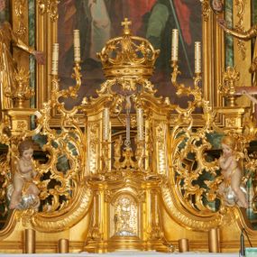 Zdjęcie nr 1: Tabernakulum w formie prostopadłościennej skrzynki o wypukłej ściance frontowej, ujęte z przodu ukośnie dostawionymi pilastrami na cokołach z trzonami w formie wolut, dźwigającymi niepełne belkowanie, opasujące je z trzech stron, nad ścianką frontową przyjmujące falistą formę zwieńczoną rocaille'm. Drzwiczki przyjmują kształt stojącego prostokąta zamkniętego łukiem półkolistym nadwieszonym, ujęte profilowaną ramą; w polu płaskorzeźbione przedstawienie kielicha z hostią w glorii na fakturowanym tle. Na belkowaniu, na osi podpór ustawiona jest para rocaille'owych lichtarzy. 
Tron wystawienia architektoniczny, trójosiowy; oś środkowa ponad tabernakulum w postaci ażurowej niszy z cokołem na pasyjkę, tylna ścianka utworzona z rocaille'u z kłosami zbóż; flankowana pilastrami zwieńczonymi falistym gzymsem, dźwigającymi ażurową, zamkniętą koronę. Podpory przechodzą w spływy wolutowe, ujmujące tabernakulum, na których końcach siedzi para adorujących puttów. Osie boczne ujęte po bokach pilastrami dźwigającymi imposty podtrzymywane przez rocaille w partii trzonów oraz płonące wazony; pola wypełnione ażurowym rocaille'm i palmetami przechodzącymi w podwójne lichtarze.
