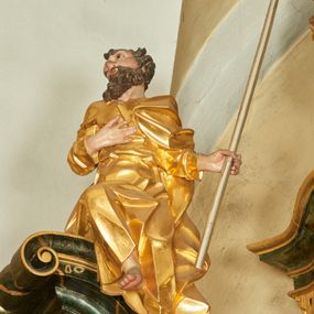 Zdjęcie nr 1: Rzeźba św. Józefa ścięta z tyłu, drążona, ustawiona na przyczółku ołtarza. Święty zwrócony trzy czwarte w prawo, ukazany w pozycji siedzącej z prawą nogą ugiętą w kolanie i delikatnie uniesioną do góry, w lewej dłoni trzyma kwitnącą laskę, a prawą ma złożoną na piersi. Twarz szeroka o wyraźnie zaznaczonych kościach policzkowych, dużych oczach i nosie, policzki i nos silnie zarumienione, twarz okolona krótką brodą. Włosy długie, ciemnobrązowe spływające na plecy i lewe ramię. Święty ubrany jest w długą suknię z długimi i wąskimi rękawami, drapowaną w grube i ostro łamane fałdy z dekoltem w kształcie litery „V”. Polichromia naturalistyczna w odsłoniętych partiach ciała; szaty złocone, laska o srebrzonym drzewcu.


