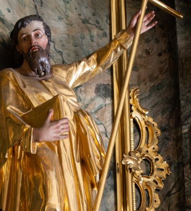 Zdjęcie nr 1: Rzeźba św. Filipa ścięta z tyłu, drążona, ustawiona na prostopadłościennej kostce. Święty ukazany frontalnie w silnym kontrapoście z prawą nogą ugiętą w kolanie. W lewej, uniesionej do góry ręce trzyma krzyż, a w prawej przytrzymuje do boku księgę. Twarz szeroka o wyraźnie zaznaczonych kościach policzkowych, dużych oczach i delikatnie rozchylonych ustach, policzki silnie zarumienione, twarz okolona długą brodą. Włosy długie, ciemnobrązowe spływające na plecy i czoło. Święty ubrany jest w suknię sięgającą do połowy łydek z długimi i wąskimi rękawami, zawiniętymi na mankietach, drapowaną w grube i miękkie fałdy. Na prawe ramię ma narzucony długi płaszcz, przewiązany diagonalnie na torsie wstążką. Polichromia naturalistyczna w odsłoniętych partiach ciała; szaty i atrybuty złocone.
