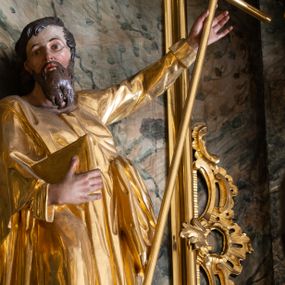 Zdjęcie nr 1: Rzeźba św. Filipa ścięta z tyłu, drążona, ustawiona na prostopadłościennej kostce. Święty ukazany frontalnie w silnym kontrapoście z prawą nogą ugiętą w kolanie. W lewej, uniesionej do góry ręce trzyma krzyż, a w prawej przytrzymuje do boku księgę. Twarz szeroka o wyraźnie zaznaczonych kościach policzkowych, dużych oczach i delikatnie rozchylonych ustach, policzki silnie zarumienione, twarz okolona długą brodą. Włosy długie, ciemnobrązowe spływające na plecy i czoło. Święty ubrany jest w suknię sięgającą do połowy łydek z długimi i wąskimi rękawami, zawiniętymi na mankietach, drapowaną w grube i miękkie fałdy. Na prawe ramię ma narzucony długi płaszcz, przewiązany diagonalnie na torsie wstążką. Polichromia naturalistyczna w odsłoniętych partiach ciała; szaty i atrybuty złocone.
