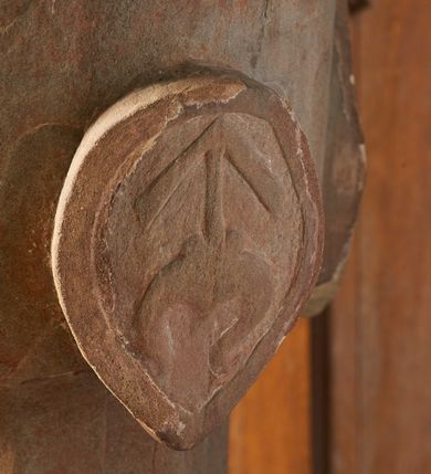 Zdjęcie nr 4: Piaskowcowa, płaskorzeźbiona chrzcielnica ustawiona na prostopadłościennym, profilowanym postumencie z uskokiem. Trzon o przekroju ośmiobocznym dekorowany płaskorzeźbionym, symetrycznym ornamentem roślinnym. Czara półkolista, puklowana; w narożach owalne tarcze z godłami herbów: Odrowąż, Gryf, Drużyna i Warna oraz syglami „S(ebastian) L(ubomirski)”. W otoku czary ornament analogiczny jak na trzonie. Pokrywa drewniana o podstawie ośmiobocznej z dekoracją płycinową. Zwieńczona przecinającymi się kabłąkami dekorowanymi kaboszonami, zamknięta kulą oraz równoramiennym krzyżem o ramionach zakończonych trójlistnie. 