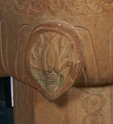 Zdjęcie nr 5: Piaskowcowa, płaskorzeźbiona chrzcielnica ustawiona na prostopadłościennym, profilowanym postumencie z uskokiem. Trzon o przekroju ośmiobocznym dekorowany płaskorzeźbionym, symetrycznym ornamentem roślinnym. Czara półkolista, puklowana; w narożach owalne tarcze z godłami herbów: Odrowąż, Gryf, Drużyna i Warna oraz syglami „S(ebastian) L(ubomirski)”. W otoku czary ornament analogiczny jak na trzonie. Pokrywa drewniana o podstawie ośmiobocznej z dekoracją płycinową. Zwieńczona przecinającymi się kabłąkami dekorowanymi kaboszonami, zamknięta kulą oraz równoramiennym krzyżem o ramionach zakończonych trójlistnie. 