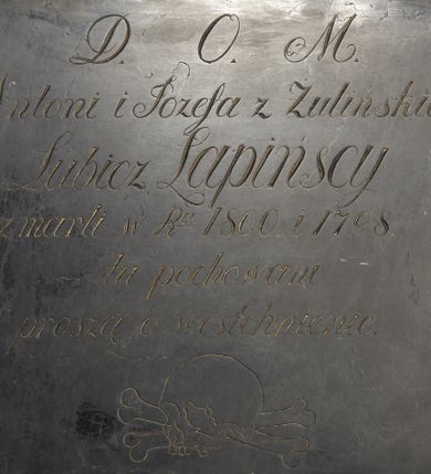 Zdjęcie nr 1: Epitafium w formie prostokątnej tablicy o kształcie zbliżonym do kwadratu z inskrypcją: „D(EO) O(PTIMO) M(AXIMO) / Antoni i Józefa z Żulińskich / Lubicz Lapińscy / Zmarli w R(ok)u 1800 i 1798 / tu pochowani / proszą o westchnienie”. Pod inskrypcją ryta czaszka ze skrzyżowanymi piszczelami.