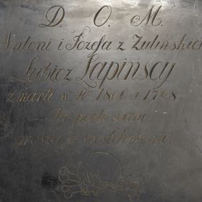 Zdjęcie nr 1: Epitafium w formie prostokątnej tablicy o kształcie zbliżonym do kwadratu z inskrypcją: „D(EO) O(PTIMO) M(AXIMO) / Antoni i Józefa z Żulińskich / Lubicz Lapińscy / Zmarli w R(ok)u 1800 i 1798 / tu pochowani / proszą o westchnienie”. Pod inskrypcją ryta czaszka ze skrzyżowanymi piszczelami.