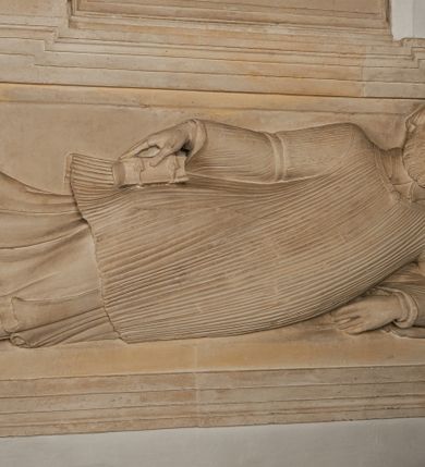 Zdjęcie nr 8: Nagrobek utworzony z dwóch położonych obok siebie płyt w formie leżącego prostokąta, w profilowanych, uszatych obramieniach z płaskorzeźbionymi, leżącymi postaciami Stanisława Lubomirskiego (po lewej) i Jakuba Lubomirskiego (po prawej). Postać po lewej leży na prawym boku, z ręką ugiętą i podpierającą głowę, zaś lewą ułożoną wzdłuż ciała, z buzdyganem w dłoni przyozdobionej pierścieniem, z ugiętą lewą nogą. Jego twarz jest pociągła, nos wydatny, ale krótki, oczy zamknięte. Włosy ma krótkie, lekko kręcone. Ubrany jest w zbroję typu husarskiego, składającą się z napierśnika z dwoma folgami brzusznymi pod szyją zakończonego wysokim kołnierzem, z naramienników, nałokietników, z sześciofolgowych taszek, nakolanników, nagolenników i butów. Na piersi zawieszony ma łańcuch. Pod nim leży hełm z pióropuszem i długi miecz. W prawym, górnym rogu kartusz z owalnym wypukłym polem z godłem herbu Drużyna i syglami w polu &quot;S&quot; i &quot;L&quot;. Nad nim kamienna tablica. 
Na prawej płycie ukazano Jakuba Lubomirskiego, leżącego na lewym boku, na ugiętej, lewej ręce i prawej ułożonej wzdłuż ciała, z księgą pod dłonią. Jego twarz jest pociągła, nos krótki, oczy zamknięte. Twarz okala długa, falista broda i wąsy, na głowie włosy sięgające uszu. Postać jest ubrana w albę i komżę. Nad płytą kamienna tablica z inskrypcją: „FVNEBRE CARME(NI) INTVMVLO REVE(REN)/DI D(OMI)NI IACOBI LVBOMIERSKI IMPRIME(N)DV(M). 
Nagrobek wieńczy czteropolowy kartusz z herbami: Drużyna, Odrowąż (Ogończyk), Warnia (Rak) i Gryf. Nad kartuszem hełm z koroną z zawieszonym u szyi krzyżem kawalerskim i ujęty labrami. 
