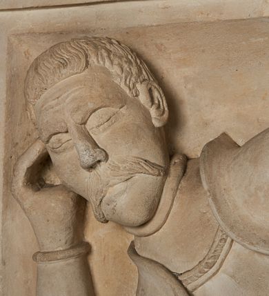 Zdjęcie nr 21: Nagrobek utworzony z dwóch położonych obok siebie płyt w formie leżącego prostokąta, w profilowanych, uszatych obramieniach z płaskorzeźbionymi, leżącymi postaciami Stanisława Lubomirskiego (po lewej) i Jakuba Lubomirskiego (po prawej). Postać po lewej leży na prawym boku, z ręką ugiętą i podpierającą głowę, zaś lewą ułożoną wzdłuż ciała, z buzdyganem w dłoni przyozdobionej pierścieniem, z ugiętą lewą nogą. Jego twarz jest pociągła, nos wydatny, ale krótki, oczy zamknięte. Włosy ma krótkie, lekko kręcone. Ubrany jest w zbroję typu husarskiego, składającą się z napierśnika z dwoma folgami brzusznymi pod szyją zakończonego wysokim kołnierzem, z naramienników, nałokietników, z sześciofolgowych taszek, nakolanników, nagolenników i butów. Na piersi zawieszony ma łańcuch. Pod nim leży hełm z pióropuszem i długi miecz. W prawym, górnym rogu kartusz z owalnym wypukłym polem z godłem herbu Drużyna i syglami w polu &quot;S&quot; i &quot;L&quot;. Nad nim kamienna tablica. 
Na prawej płycie ukazano Jakuba Lubomirskiego, leżącego na lewym boku, na ugiętej, lewej ręce i prawej ułożonej wzdłuż ciała, z księgą pod dłonią. Jego twarz jest pociągła, nos krótki, oczy zamknięte. Twarz okala długa, falista broda i wąsy, na głowie włosy sięgające uszu. Postać jest ubrana w albę i komżę. Nad płytą kamienna tablica z inskrypcją: „FVNEBRE CARME(NI) INTVMVLO REVE(REN)/DI D(OMI)NI IACOBI LVBOMIERSKI IMPRIME(N)DV(M). 
Nagrobek wieńczy czteropolowy kartusz z herbami: Drużyna, Odrowąż (Ogończyk), Warnia (Rak) i Gryf. Nad kartuszem hełm z koroną z zawieszonym u szyi krzyżem kawalerskim i ujęty labrami. 
