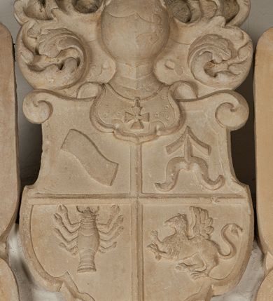 Zdjęcie nr 15: Nagrobek utworzony z dwóch położonych obok siebie płyt w formie leżącego prostokąta, w profilowanych, uszatych obramieniach z płaskorzeźbionymi, leżącymi postaciami Stanisława Lubomirskiego (po lewej) i Jakuba Lubomirskiego (po prawej). Postać po lewej leży na prawym boku, z ręką ugiętą i podpierającą głowę, zaś lewą ułożoną wzdłuż ciała, z buzdyganem w dłoni przyozdobionej pierścieniem, z ugiętą lewą nogą. Jego twarz jest pociągła, nos wydatny, ale krótki, oczy zamknięte. Włosy ma krótkie, lekko kręcone. Ubrany jest w zbroję typu husarskiego, składającą się z napierśnika z dwoma folgami brzusznymi pod szyją zakończonego wysokim kołnierzem, z naramienników, nałokietników, z sześciofolgowych taszek, nakolanników, nagolenników i butów. Na piersi zawieszony ma łańcuch. Pod nim leży hełm z pióropuszem i długi miecz. W prawym, górnym rogu kartusz z owalnym wypukłym polem z godłem herbu Drużyna i syglami w polu &quot;S&quot; i &quot;L&quot;. Nad nim kamienna tablica. 
Na prawej płycie ukazano Jakuba Lubomirskiego, leżącego na lewym boku, na ugiętej, lewej ręce i prawej ułożonej wzdłuż ciała, z księgą pod dłonią. Jego twarz jest pociągła, nos krótki, oczy zamknięte. Twarz okala długa, falista broda i wąsy, na głowie włosy sięgające uszu. Postać jest ubrana w albę i komżę. Nad płytą kamienna tablica z inskrypcją: „FVNEBRE CARME(NI) INTVMVLO REVE(REN)/DI D(OMI)NI IACOBI LVBOMIERSKI IMPRIME(N)DV(M). 
Nagrobek wieńczy czteropolowy kartusz z herbami: Drużyna, Odrowąż (Ogończyk), Warnia (Rak) i Gryf. Nad kartuszem hełm z koroną z zawieszonym u szyi krzyżem kawalerskim i ujęty labrami. 
