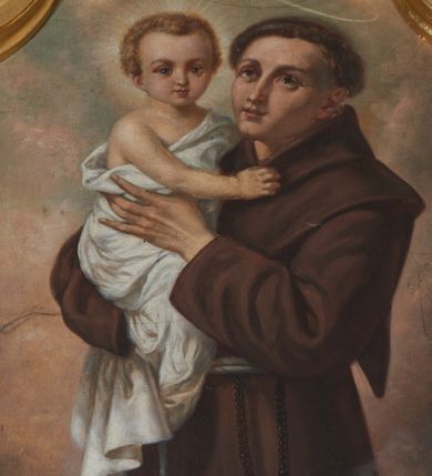 Zdjęcie nr 1: Obraz w kształcie stojącego prostokąta zamkniętego łukiem nadwieszonym z uskokiem, ujęty złoconą, profilowaną ramą. W centrum kompozycji przedstawienie ukazanego w półpostaci, zwróconego w trzech czwartych w prawo św. Antoniego trzymającego na ręku Dzieciątko Jezus. Święty ukazany jako mężczyzna o twarzy pozbawionej zarostu, z tonsurą na głowie, ubrany w brązowy habit przepasany sznurem. U jego boku widoczny różaniec. Święty Antoni oburącz podtrzymuje jasnowłosego Jezusa. Dzieciątko owinięte białą tkaniną. Ponad głową świętego aureola, wokół głowy Dzieciątka nimb promienisty. W dolnej części kompozycji widoczny kwiat białej lilii. Tło jednolicie żółto-brązowe. Kolorystyka obrazu ciemna, ciepła z dominacją brązu.