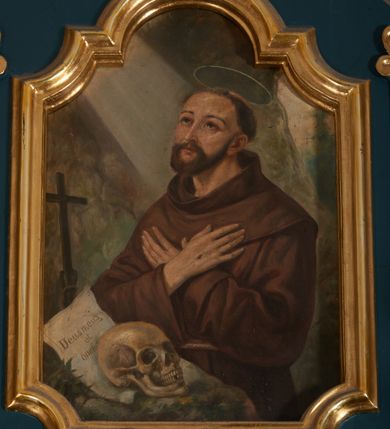 Zdjęcie nr 15: Ołtarz przyścienny, architektoniczny, dwukondygnacyjny, jednoosiowy. Mensa prostopadłościenna, antepedium haftowane z motywem serca gorejącego ujętego winnymi gronami oraz kłosami. Na  mensie architektoniczne, ujęte kolumnami tabernakulum z płaskorzeźbionym kielichem i hostią na drzwiczkach. W pierwszej kondygnacji obraz w kształcie stojącego prostokąta o uskokowo ściętych, górnych narożach z przedstawieniem św. Anny Samotrzeć (na zasuwie obraz „Najświętsze Serce Jezusa”) ujęty umieszczonymi na postumentach, kręconymi, złoconymi  i srebrzonymi kolumnami o kompozytowych kapitelach ustawionymi na tle kanelowanych pilastrów. Podpory dźwigają pełne, wyłamane belkowanie zwieńczone wydatnym, profilowanym gzymsem. Na osiach podpór pełnoplastyczne figury aniołów na obłokach. Fryz dekorowany rozetami oraz uskrzydloną główką anielską. W drugiej kondygnacji obraz św. Franciszka w ramie zamkniętej łukiem półkolistym wyniesionym, z uskokiem. Szczyt w formie przerwanego przyczółka, na osi którego krzyż. Całość nastawy ujęta ażurowymi uszami uformowanymi  z suchego akantu oraz wstęgi. Dekoracja akantowa, rozety, pola wypełnione kratą. Struktura nastawy w odcieniu ciemnej, morskiej zieleni, ornament złocony i srebrzony. 