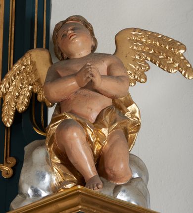 Zdjęcie nr 18: Ołtarz przyścienny, architektoniczny, dwukondygnacyjny, jednoosiowy. Mensa prostopadłościenna, antepedium haftowane z motywem serca gorejącego ujętego winnymi gronami oraz kłosami. Na  mensie architektoniczne, ujęte kolumnami tabernakulum z płaskorzeźbionym kielichem i hostią na drzwiczkach. W pierwszej kondygnacji obraz w kształcie stojącego prostokąta o uskokowo ściętych, górnych narożach z przedstawieniem św. Anny Samotrzeć (na zasuwie obraz „Najświętsze Serce Jezusa”) ujęty umieszczonymi na postumentach, kręconymi, złoconymi  i srebrzonymi kolumnami o kompozytowych kapitelach ustawionymi na tle kanelowanych pilastrów. Podpory dźwigają pełne, wyłamane belkowanie zwieńczone wydatnym, profilowanym gzymsem. Na osiach podpór pełnoplastyczne figury aniołów na obłokach. Fryz dekorowany rozetami oraz uskrzydloną główką anielską. W drugiej kondygnacji obraz św. Franciszka w ramie zamkniętej łukiem półkolistym wyniesionym, z uskokiem. Szczyt w formie przerwanego przyczółka, na osi którego krzyż. Całość nastawy ujęta ażurowymi uszami uformowanymi  z suchego akantu oraz wstęgi. Dekoracja akantowa, rozety, pola wypełnione kratą. Struktura nastawy w odcieniu ciemnej, morskiej zieleni, ornament złocony i srebrzony. 