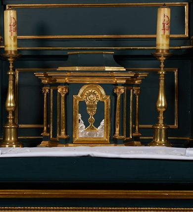 Zdjęcie nr 20: Ołtarz przyścienny, architektoniczny, dwukondygnacyjny, jednoosiowy. Mensa prostopadłościenna, antepedium haftowane z motywem serca gorejącego ujętego winnymi gronami oraz kłosami. Na  mensie architektoniczne, ujęte kolumnami tabernakulum z płaskorzeźbionym kielichem i hostią na drzwiczkach. W pierwszej kondygnacji obraz w kształcie stojącego prostokąta o uskokowo ściętych, górnych narożach z przedstawieniem św. Anny Samotrzeć (na zasuwie obraz „Najświętsze Serce Jezusa”) ujęty umieszczonymi na postumentach, kręconymi, złoconymi  i srebrzonymi kolumnami o kompozytowych kapitelach ustawionymi na tle kanelowanych pilastrów. Podpory dźwigają pełne, wyłamane belkowanie zwieńczone wydatnym, profilowanym gzymsem. Na osiach podpór pełnoplastyczne figury aniołów na obłokach. Fryz dekorowany rozetami oraz uskrzydloną główką anielską. W drugiej kondygnacji obraz św. Franciszka w ramie zamkniętej łukiem półkolistym wyniesionym, z uskokiem. Szczyt w formie przerwanego przyczółka, na osi którego krzyż. Całość nastawy ujęta ażurowymi uszami uformowanymi  z suchego akantu oraz wstęgi. Dekoracja akantowa, rozety, pola wypełnione kratą. Struktura nastawy w odcieniu ciemnej, morskiej zieleni, ornament złocony i srebrzony. 