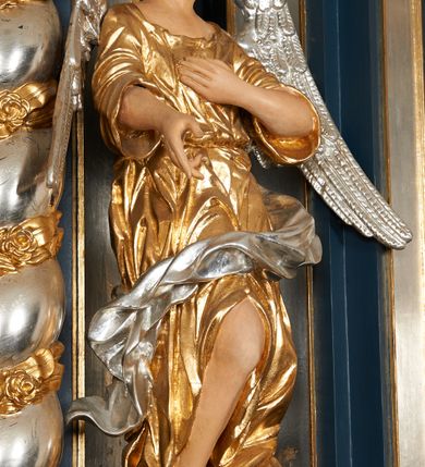 Zdjęcie nr 14: Ołtarz architektoniczny, trójosiowy, jednokondygnacyjny ze zwieńczeniem, na cokole. Mensa kamienna z portatylem. Antepedium proste, bez dekoracji, kamienne. Tabernakulum prostopadłościenne, ujęte pilastrami ustawionymi pod kątem, ze zwróconymi przeciwstawnie wolutami, zamiast trzonów, zwieńczone niepełnym belkowaniem. Drzwiczki w formie stojącego prostokąta zamkniętego łukiem półkolistym z krzyżem w polu. Retabulum ujęte parami pilastrów i kolumn o skręconych trzonach oraz kapitelach kompozytowych, dźwigających niepełne belkowanie z wydatnym gzymsem, wyłamanym w osiach podpór, przerwane w polu środkowym. Na gzymsie para puttów trzymających arma Christi. Osie boczne ustawione pod kątem względem lica ołtarza, w nich ustawiony dwie figury stojących aniołów. W polu środkowym ołtarza rama w formie stojącego prostokąta mieszcząca obraz św. Teresy z Lisieux. Zwieńczenie ołtarza w kształcie owalnego medalionu ujętego wydatnymi spływami wolutowymi. W polu owalny obraz przedstawiający wskrzeszenie Piotrowina. Kondygnacja pierwsza nastawy ujęta uszami utworzonymi z akantu. Cokoły podpór ozdobione z trzech stron płycinami z dekoracją roślinną w postaci liści i kwiatów. Na osi pilastrów cokoły podparte potrójną wolutą i parą girland owocowych. Trzony pilastrów i osie boczne dekorowane płycinami. Trzony kolumn zdobione ornamentem roślinnym. W polu środkowym ołtarza rama obrazu dekorowana akantem; u jej spodu akant i uskrzydlona główka anielska, zwieńczona akantem z palmetą. W zwieńczeniu profilowana rama dekorowana miejscami akantem, ujęta muszlą; woluty i lizeny zdobione kampanulami. Struktura ołtarza polichromowana na ciemnogranatowo ze złoconymi i srebrzonymi elementami architektonicznymi i ornamentyką.