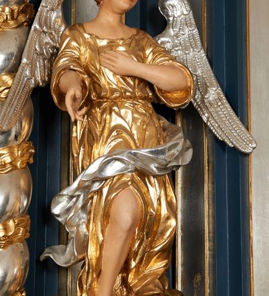 Zdjęcie nr 9: Ołtarz architektoniczny, trójosiowy, jednokondygnacyjny ze zwieńczeniem, na cokole. Mensa kamienna z portatylem. Antepedium proste, bez dekoracji, kamienne. Tabernakulum prostopadłościenne, ujęte pilastrami ustawionymi pod kątem, ze zwróconymi przeciwstawnie wolutami, zamiast trzonów, zwieńczone niepełnym belkowaniem. Drzwiczki w formie stojącego prostokąta zamkniętego łukiem półkolistym z krzyżem w polu. Retabulum ujęte parami pilastrów i kolumn o skręconych trzonach oraz kapitelach kompozytowych, dźwigających niepełne belkowanie z wydatnym gzymsem, wyłamanym w osiach podpór, przerwane w polu środkowym. Na gzymsie para puttów trzymających arma Christi. Osie boczne ustawione pod kątem względem lica ołtarza, w nich ustawiony dwie figury stojących aniołów. W polu środkowym ołtarza rama w formie stojącego prostokąta mieszcząca obraz św. Teresy z Lisieux. Zwieńczenie ołtarza w kształcie owalnego medalionu ujętego wydatnymi spływami wolutowymi. W polu owalny obraz przedstawiający wskrzeszenie Piotrowina. Kondygnacja pierwsza nastawy ujęta uszami utworzonymi z akantu. Cokoły podpór ozdobione z trzech stron płycinami z dekoracją roślinną w postaci liści i kwiatów. Na osi pilastrów cokoły podparte potrójną wolutą i parą girland owocowych. Trzony pilastrów i osie boczne dekorowane płycinami. Trzony kolumn zdobione ornamentem roślinnym. W polu środkowym ołtarza rama obrazu dekorowana akantem; u jej spodu akant i uskrzydlona główka anielska, zwieńczona akantem z palmetą. W zwieńczeniu profilowana rama dekorowana miejscami akantem, ujęta muszlą; woluty i lizeny zdobione kampanulami. Struktura ołtarza polichromowana na ciemnogranatowo ze złoconymi i srebrzonymi elementami architektonicznymi i ornamentyką.