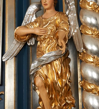 Zdjęcie nr 4: Ołtarz architektoniczny, trójosiowy, jednokondygnacyjny ze zwieńczeniem, na cokole. Mensa kamienna z portatylem. Antepedium proste, bez dekoracji, kamienne. Tabernakulum prostopadłościenne, ujęte pilastrami ustawionymi pod kątem, ze zwróconymi przeciwstawnie wolutami, zamiast trzonów, zwieńczone niepełnym belkowaniem. Drzwiczki w formie stojącego prostokąta zamkniętego łukiem półkolistym z krzyżem w polu. Retabulum ujęte parami pilastrów i kolumn o skręconych trzonach oraz kapitelach kompozytowych, dźwigających niepełne belkowanie z wydatnym gzymsem, wyłamanym w osiach podpór, przerwane w polu środkowym. Na gzymsie para puttów trzymających arma Christi. Osie boczne ustawione pod kątem względem lica ołtarza, w nich ustawiony dwie figury stojących aniołów. W polu środkowym ołtarza rama w formie stojącego prostokąta mieszcząca obraz św. Teresy z Lisieux. Zwieńczenie ołtarza w kształcie owalnego medalionu ujętego wydatnymi spływami wolutowymi. W polu owalny obraz przedstawiający wskrzeszenie Piotrowina. Kondygnacja pierwsza nastawy ujęta uszami utworzonymi z akantu. Cokoły podpór ozdobione z trzech stron płycinami z dekoracją roślinną w postaci liści i kwiatów. Na osi pilastrów cokoły podparte potrójną wolutą i parą girland owocowych. Trzony pilastrów i osie boczne dekorowane płycinami. Trzony kolumn zdobione ornamentem roślinnym. W polu środkowym ołtarza rama obrazu dekorowana akantem; u jej spodu akant i uskrzydlona główka anielska, zwieńczona akantem z palmetą. W zwieńczeniu profilowana rama dekorowana miejscami akantem, ujęta muszlą; woluty i lizeny zdobione kampanulami. Struktura ołtarza polichromowana na ciemnogranatowo ze złoconymi i srebrzonymi elementami architektonicznymi i ornamentyką.