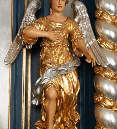 Zdjęcie nr 5: Ołtarz architektoniczny, trójosiowy, jednokondygnacyjny ze zwieńczeniem, na cokole. Mensa kamienna z portatylem. Antepedium proste, bez dekoracji, kamienne. Tabernakulum prostopadłościenne, ujęte pilastrami ustawionymi pod kątem, ze zwróconymi przeciwstawnie wolutami, zamiast trzonów, zwieńczone niepełnym belkowaniem. Drzwiczki w formie stojącego prostokąta zamkniętego łukiem półkolistym z krzyżem w polu. Retabulum ujęte parami pilastrów i kolumn o skręconych trzonach oraz kapitelach kompozytowych, dźwigających niepełne belkowanie z wydatnym gzymsem, wyłamanym w osiach podpór, przerwane w polu środkowym. Na gzymsie para puttów trzymających arma Christi. Osie boczne ustawione pod kątem względem lica ołtarza, w nich ustawiony dwie figury stojących aniołów. W polu środkowym ołtarza rama w formie stojącego prostokąta mieszcząca obraz św. Teresy z Lisieux. Zwieńczenie ołtarza w kształcie owalnego medalionu ujętego wydatnymi spływami wolutowymi. W polu owalny obraz przedstawiający wskrzeszenie Piotrowina. Kondygnacja pierwsza nastawy ujęta uszami utworzonymi z akantu. Cokoły podpór ozdobione z trzech stron płycinami z dekoracją roślinną w postaci liści i kwiatów. Na osi pilastrów cokoły podparte potrójną wolutą i parą girland owocowych. Trzony pilastrów i osie boczne dekorowane płycinami. Trzony kolumn zdobione ornamentem roślinnym. W polu środkowym ołtarza rama obrazu dekorowana akantem; u jej spodu akant i uskrzydlona główka anielska, zwieńczona akantem z palmetą. W zwieńczeniu profilowana rama dekorowana miejscami akantem, ujęta muszlą; woluty i lizeny zdobione kampanulami. Struktura ołtarza polichromowana na ciemnogranatowo ze złoconymi i srebrzonymi elementami architektonicznymi i ornamentyką.