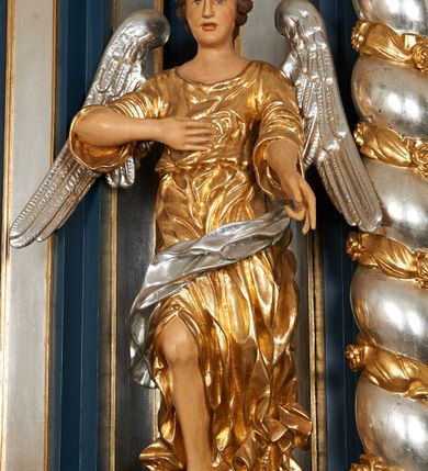 Zdjęcie nr 3: Ołtarz architektoniczny, trójosiowy, jednokondygnacyjny ze zwieńczeniem, na cokole. Mensa kamienna z portatylem. Antepedium proste, bez dekoracji, kamienne. Tabernakulum prostopadłościenne, ujęte pilastrami ustawionymi pod kątem, ze zwróconymi przeciwstawnie wolutami, zamiast trzonów, zwieńczone niepełnym belkowaniem. Drzwiczki w formie stojącego prostokąta zamkniętego łukiem półkolistym z krzyżem w polu. Retabulum ujęte parami pilastrów i kolumn o skręconych trzonach oraz kapitelach kompozytowych, dźwigających niepełne belkowanie z wydatnym gzymsem, wyłamanym w osiach podpór, przerwane w polu środkowym. Na gzymsie para puttów trzymających arma Christi. Osie boczne ustawione pod kątem względem lica ołtarza, w nich ustawiony dwie figury stojących aniołów. W polu środkowym ołtarza rama w formie stojącego prostokąta mieszcząca obraz św. Teresy z Lisieux. Zwieńczenie ołtarza w kształcie owalnego medalionu ujętego wydatnymi spływami wolutowymi. W polu owalny obraz przedstawiający wskrzeszenie Piotrowina. Kondygnacja pierwsza nastawy ujęta uszami utworzonymi z akantu. Cokoły podpór ozdobione z trzech stron płycinami z dekoracją roślinną w postaci liści i kwiatów. Na osi pilastrów cokoły podparte potrójną wolutą i parą girland owocowych. Trzony pilastrów i osie boczne dekorowane płycinami. Trzony kolumn zdobione ornamentem roślinnym. W polu środkowym ołtarza rama obrazu dekorowana akantem; u jej spodu akant i uskrzydlona główka anielska, zwieńczona akantem z palmetą. W zwieńczeniu profilowana rama dekorowana miejscami akantem, ujęta muszlą; woluty i lizeny zdobione kampanulami. Struktura ołtarza polichromowana na ciemnogranatowo ze złoconymi i srebrzonymi elementami architektonicznymi i ornamentyką.